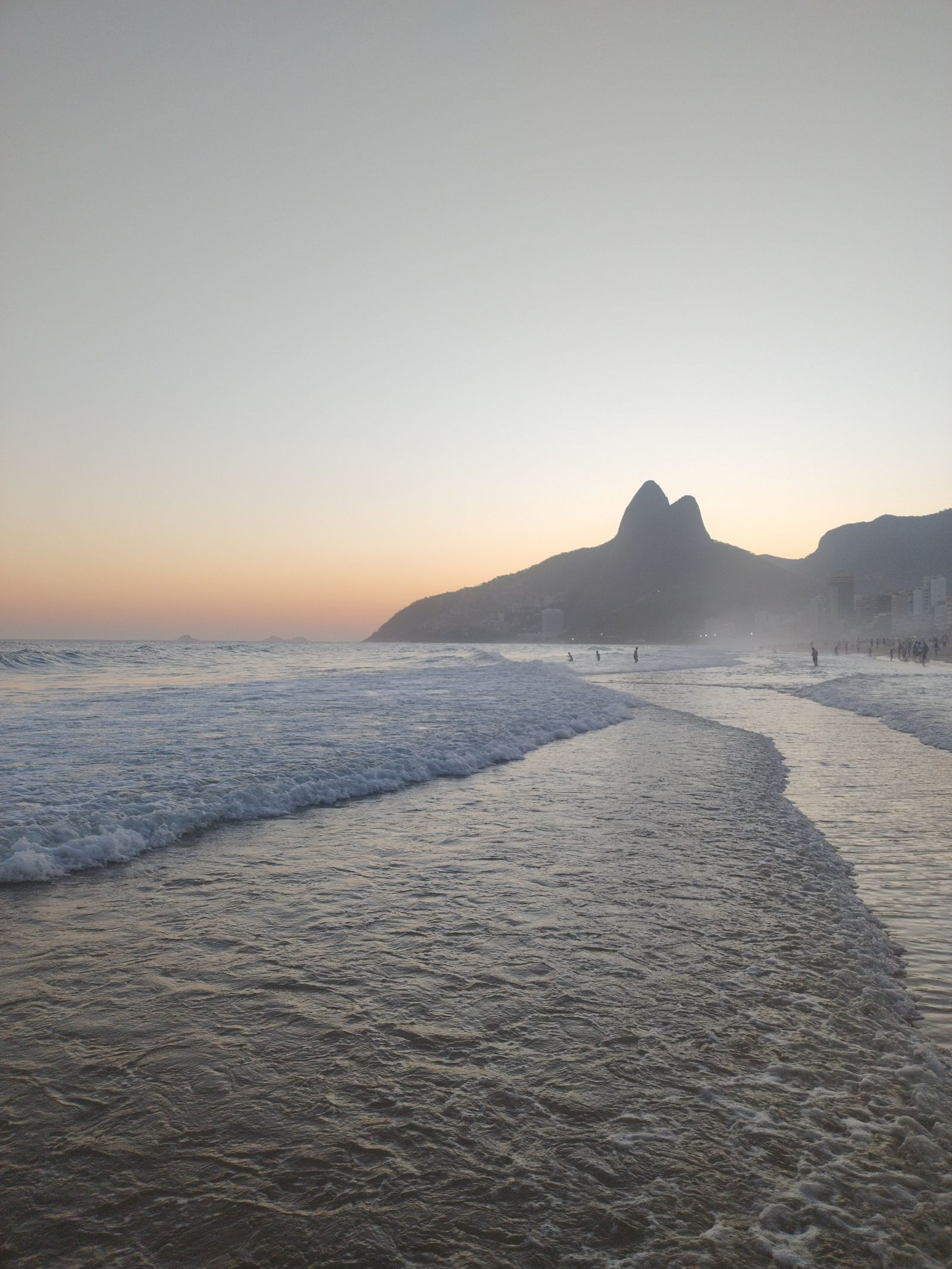 Sunset over Ipanema Beach with waves and the Dois Irmaos peaks