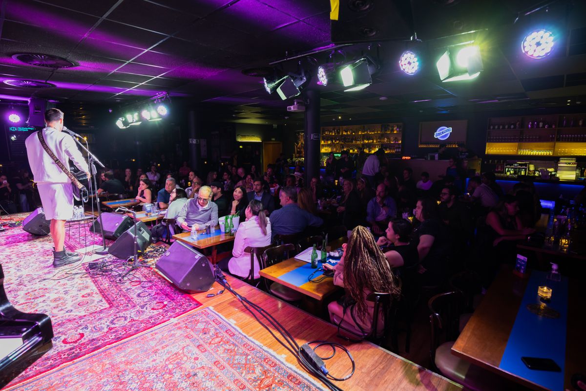 A live music venue in full swing, the band on stage and every table taken