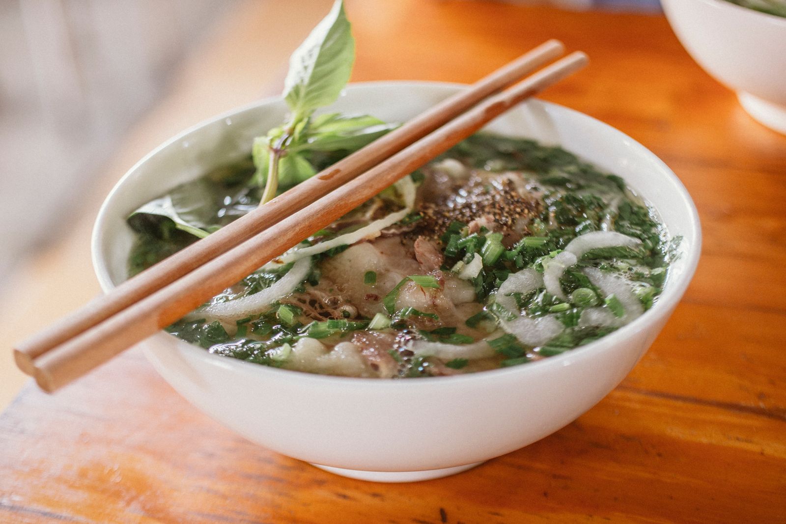 Vietnamese pho with beef and fresh herbs in a ceramic bowl