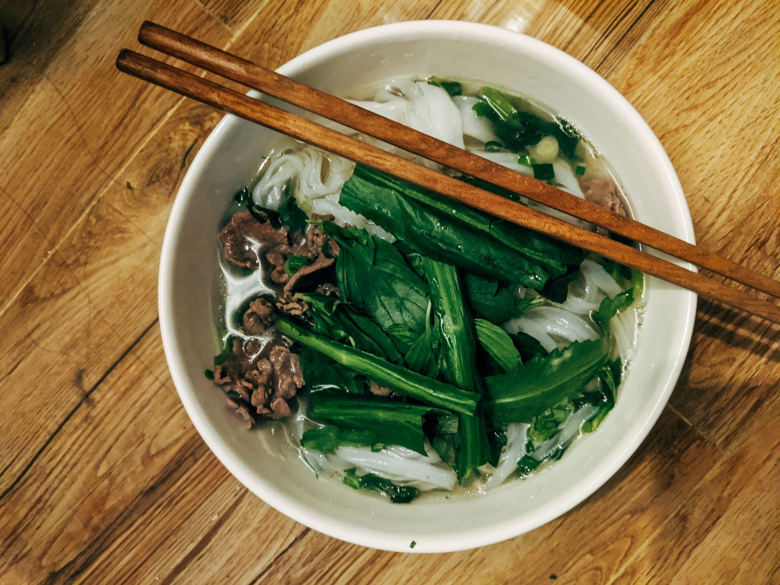 Vietnam food guide: a bowl of pho with fresh herbs and chopsticks