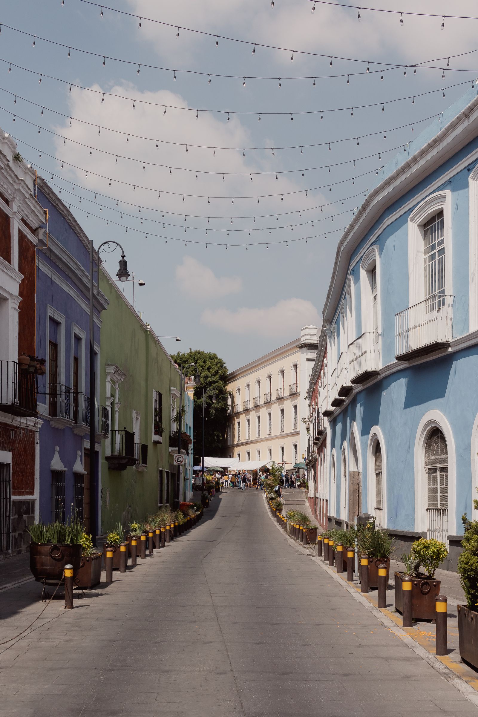 A colonial street in Puebla, Mexico, with colourful buildings and potted plants