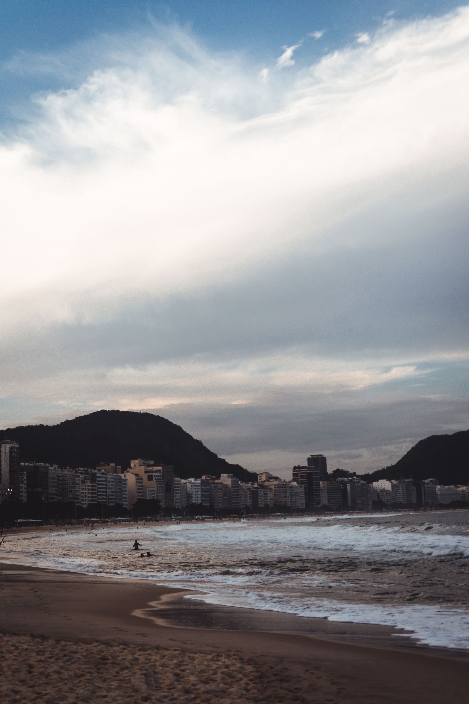Copacabana Beach in Rio de Janeiro at dusk with ocean waves and city skyline