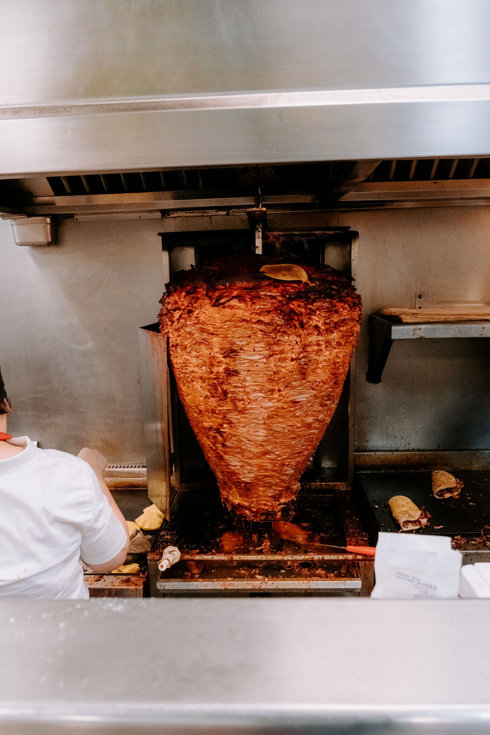 A spit of marinated al pastor meat in a traditional kitchen