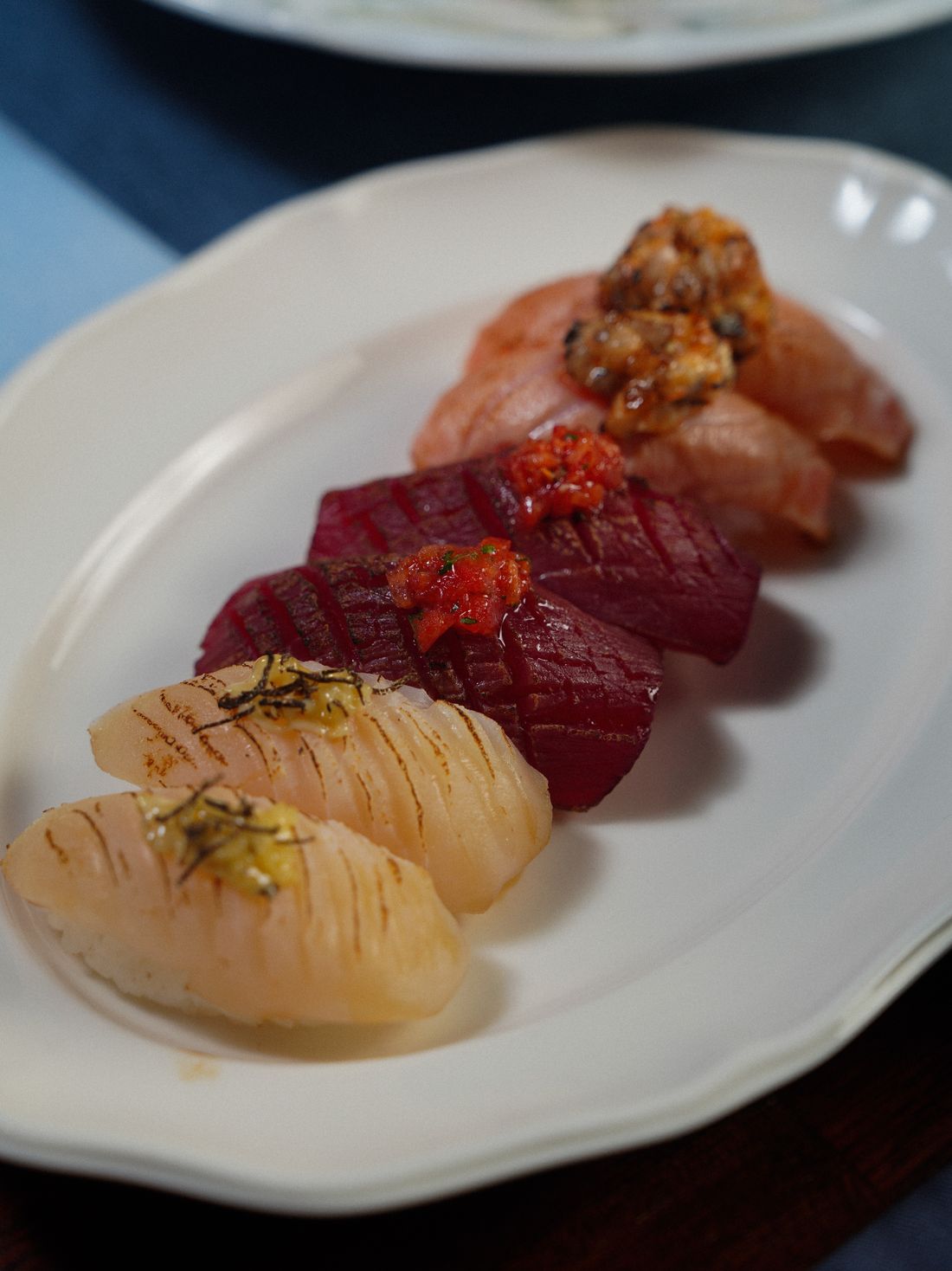 An assortment of nigiri with tuna and salmon on a pale plate
