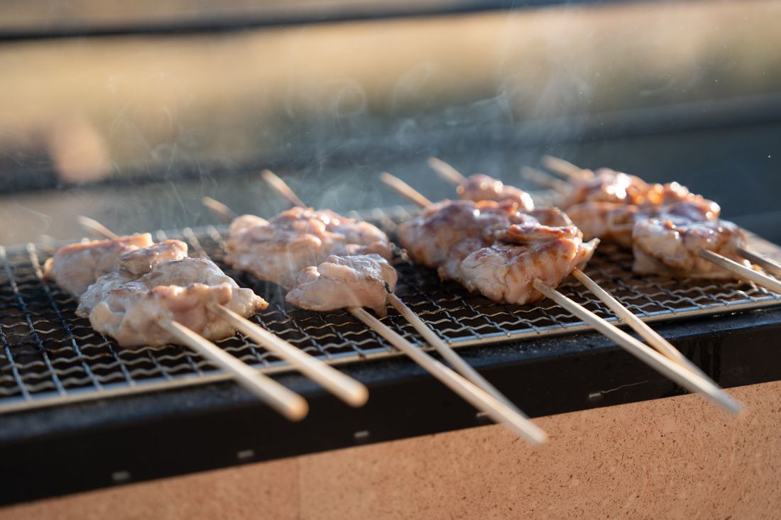 Skewers cooking in a row over a grill
