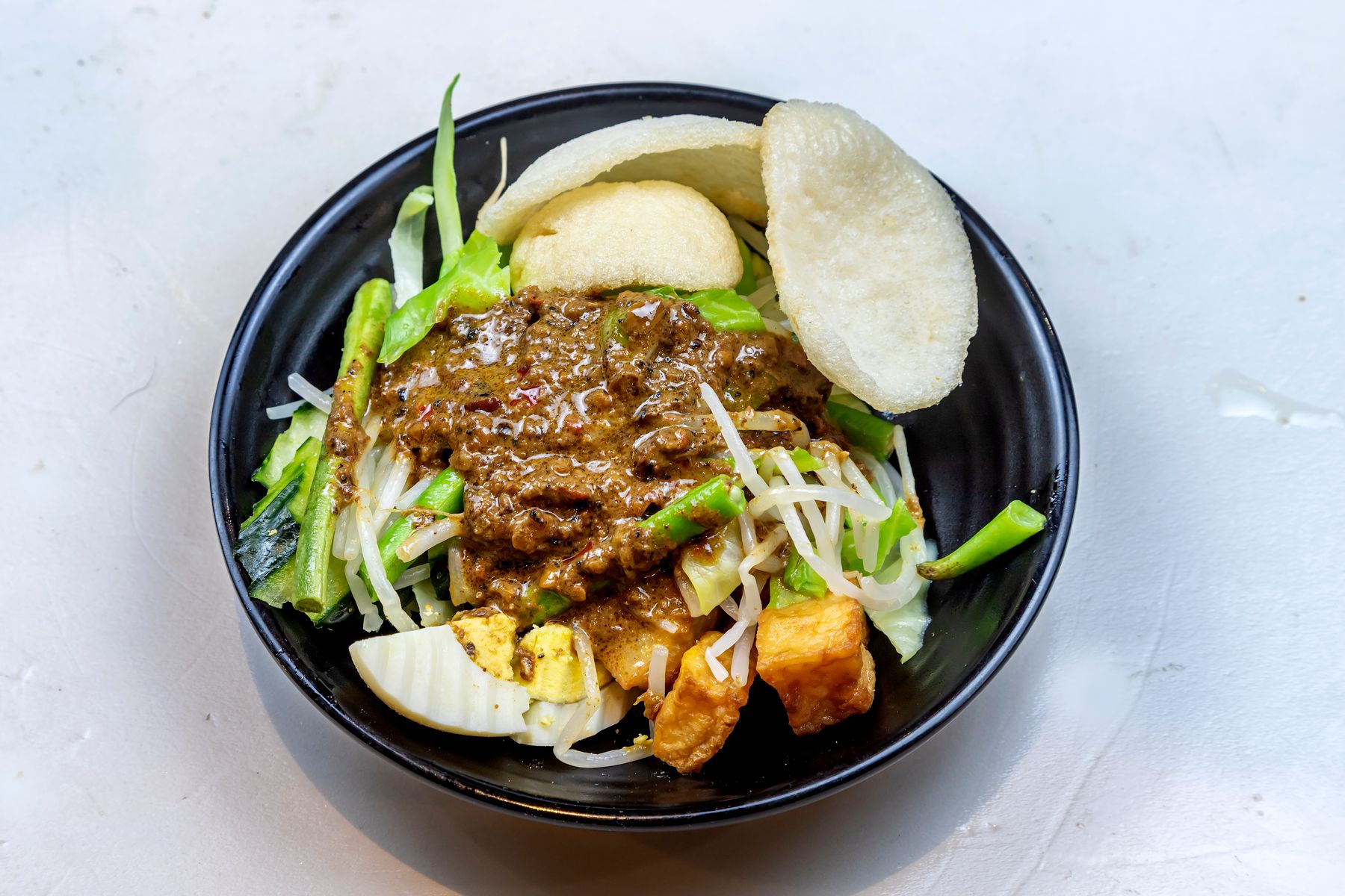 Blanched vegetables, tofu and egg in a bowl with peanut sauce