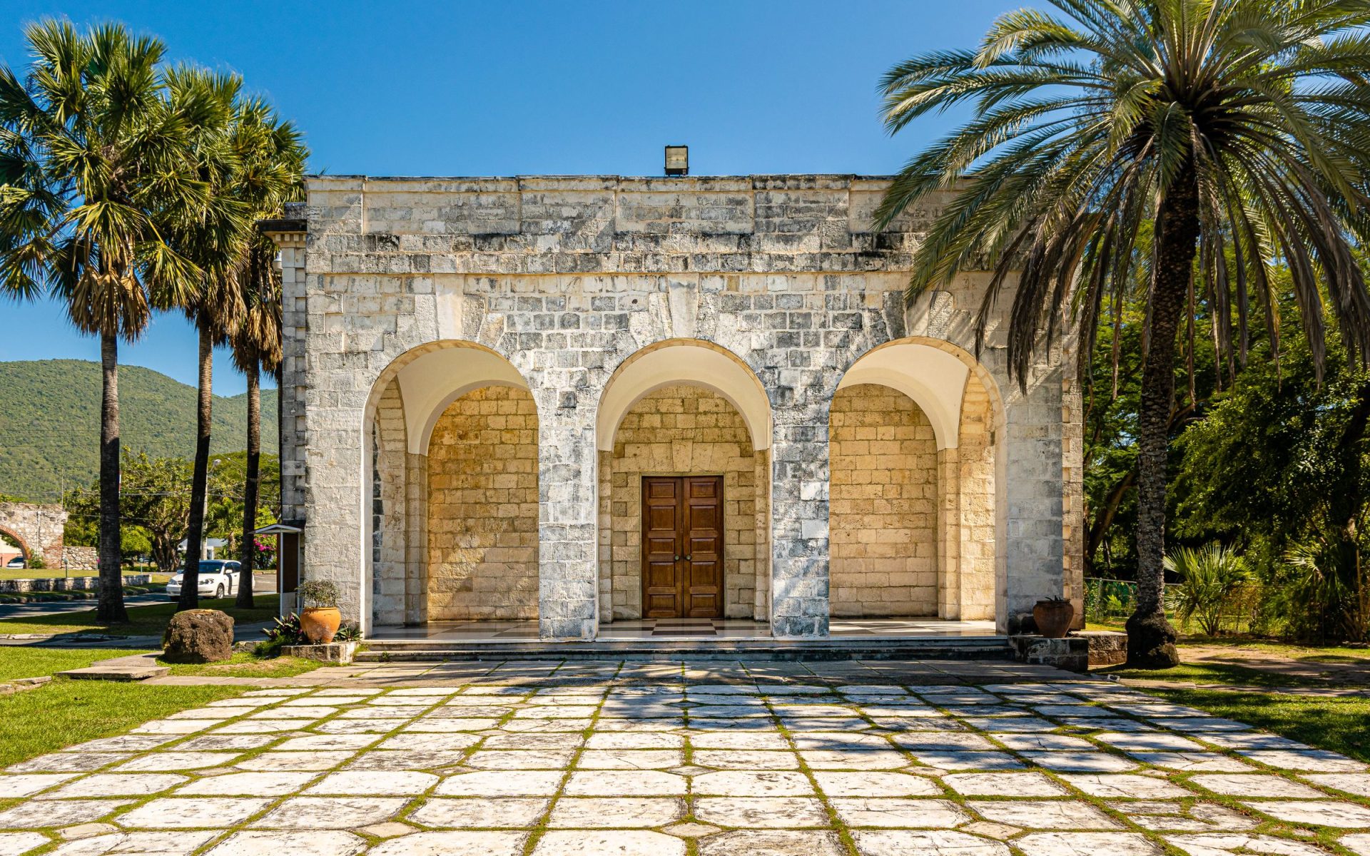Old stone structure with an arched entrance surrounded by palm trees in Kingston, Jamaica