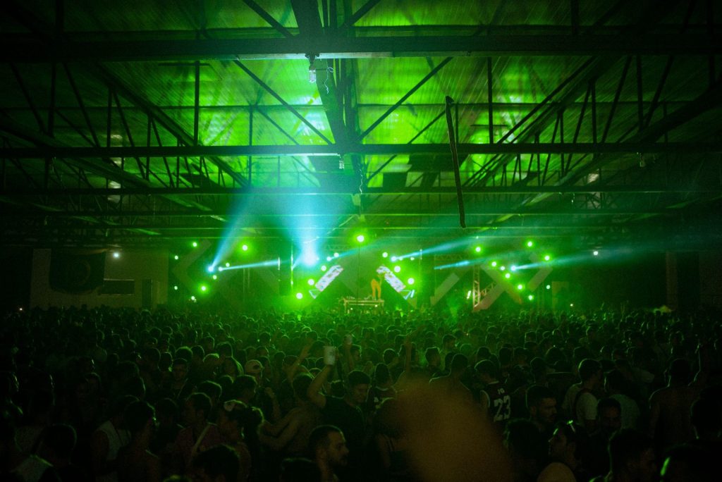 Green stage lights over a crowd on a club dance floor
