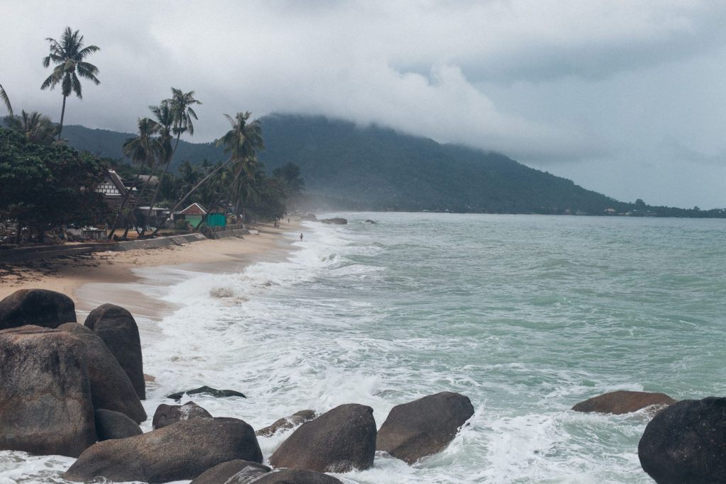 Best party islands in Thailand guide: a palm-lined rocky island beach by day