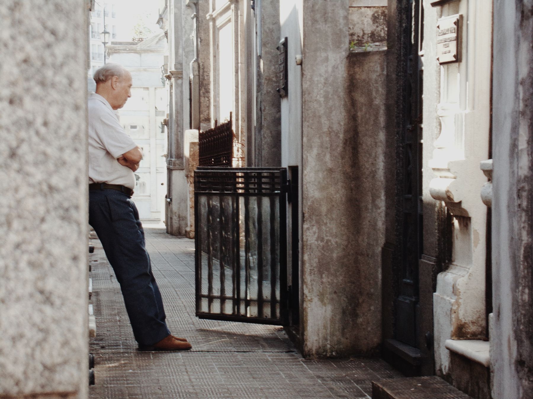 An elderly man walking an alleyway of mausoleums in a Buenos Aires cemetery