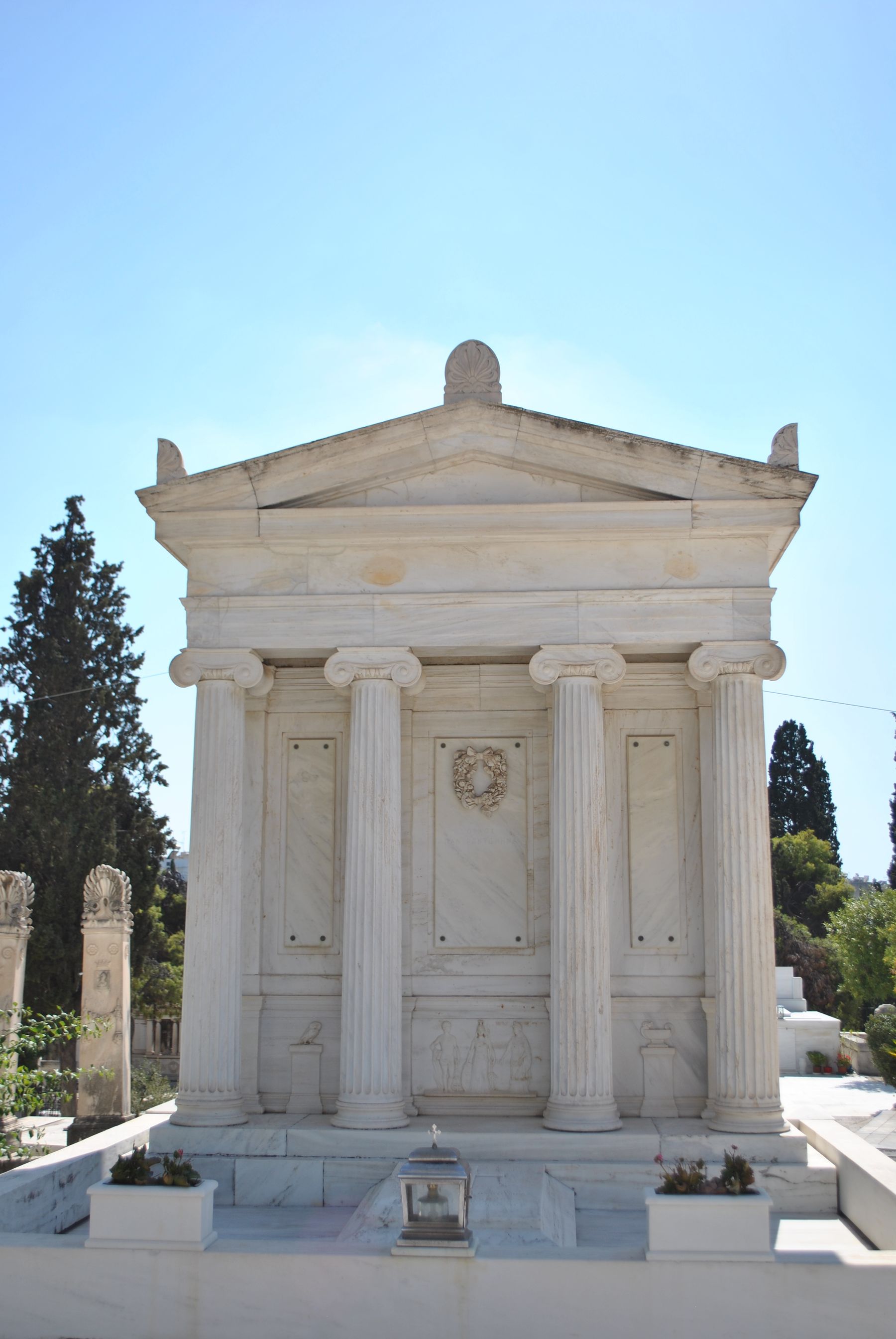 A classic marble mausoleum with columns in an outdoor cemetery