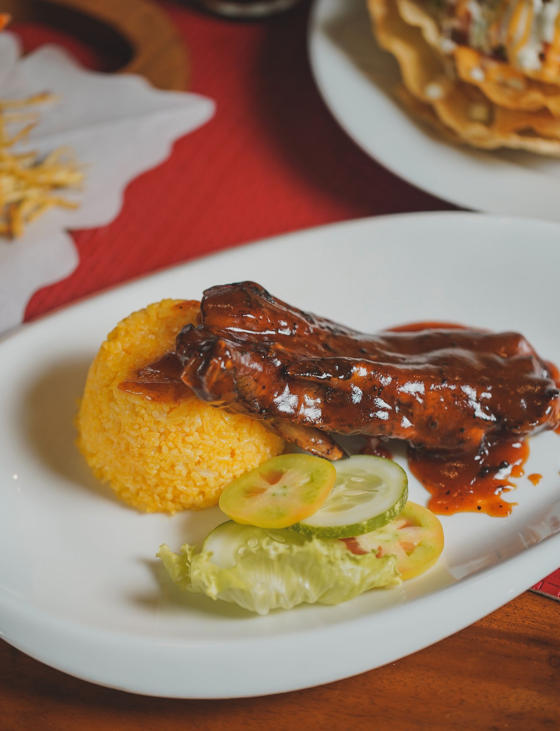 Barbecued ribs with rice and a fresh salad on a white plate