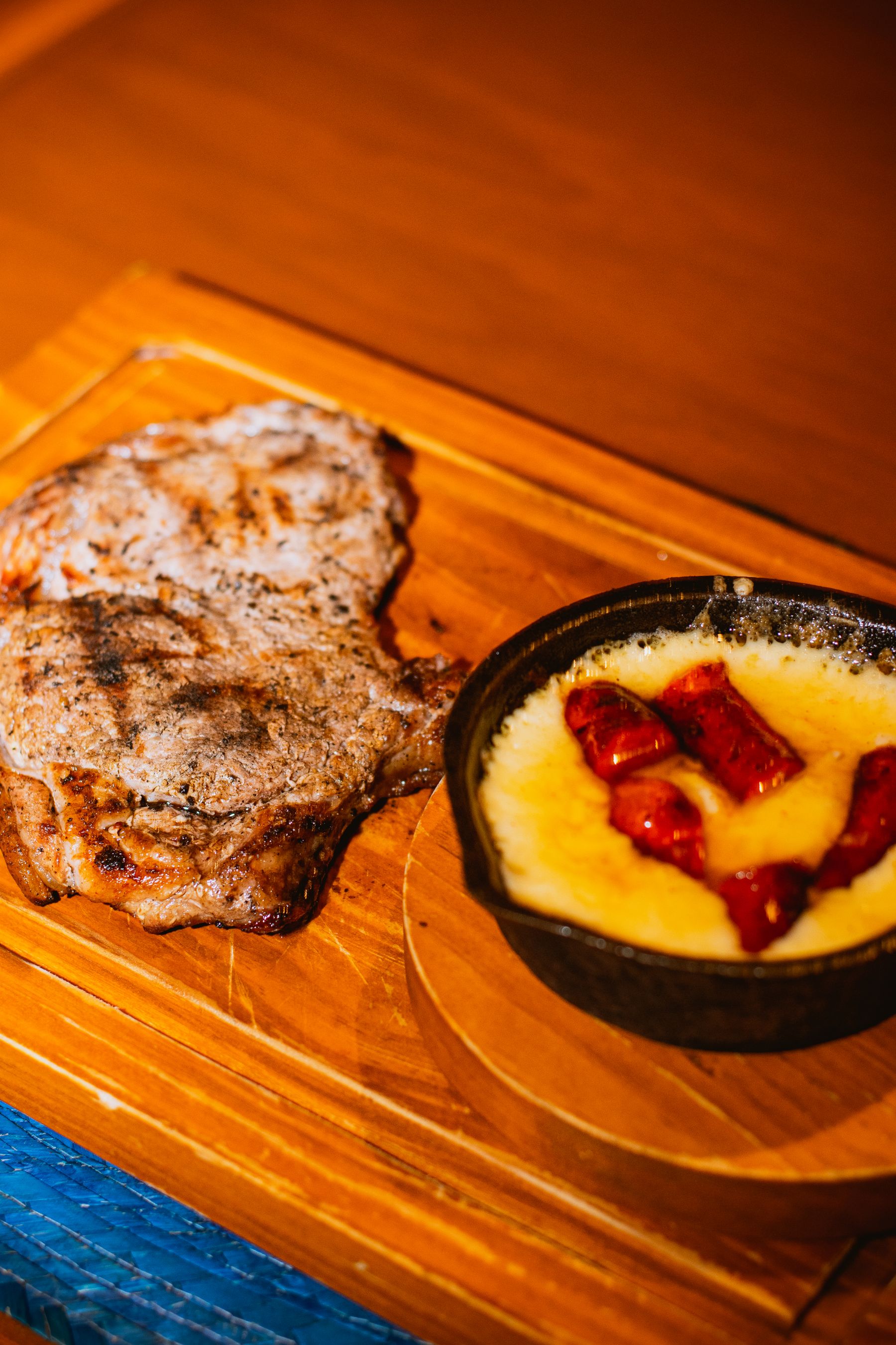 A grilled steak with a creamy cheesy corn side served on a wooden board