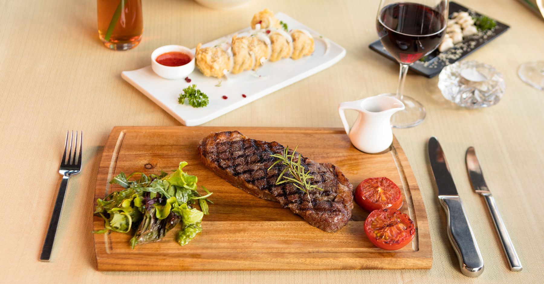 A steak served with grilled tomatoes, salad and a glass of red wine