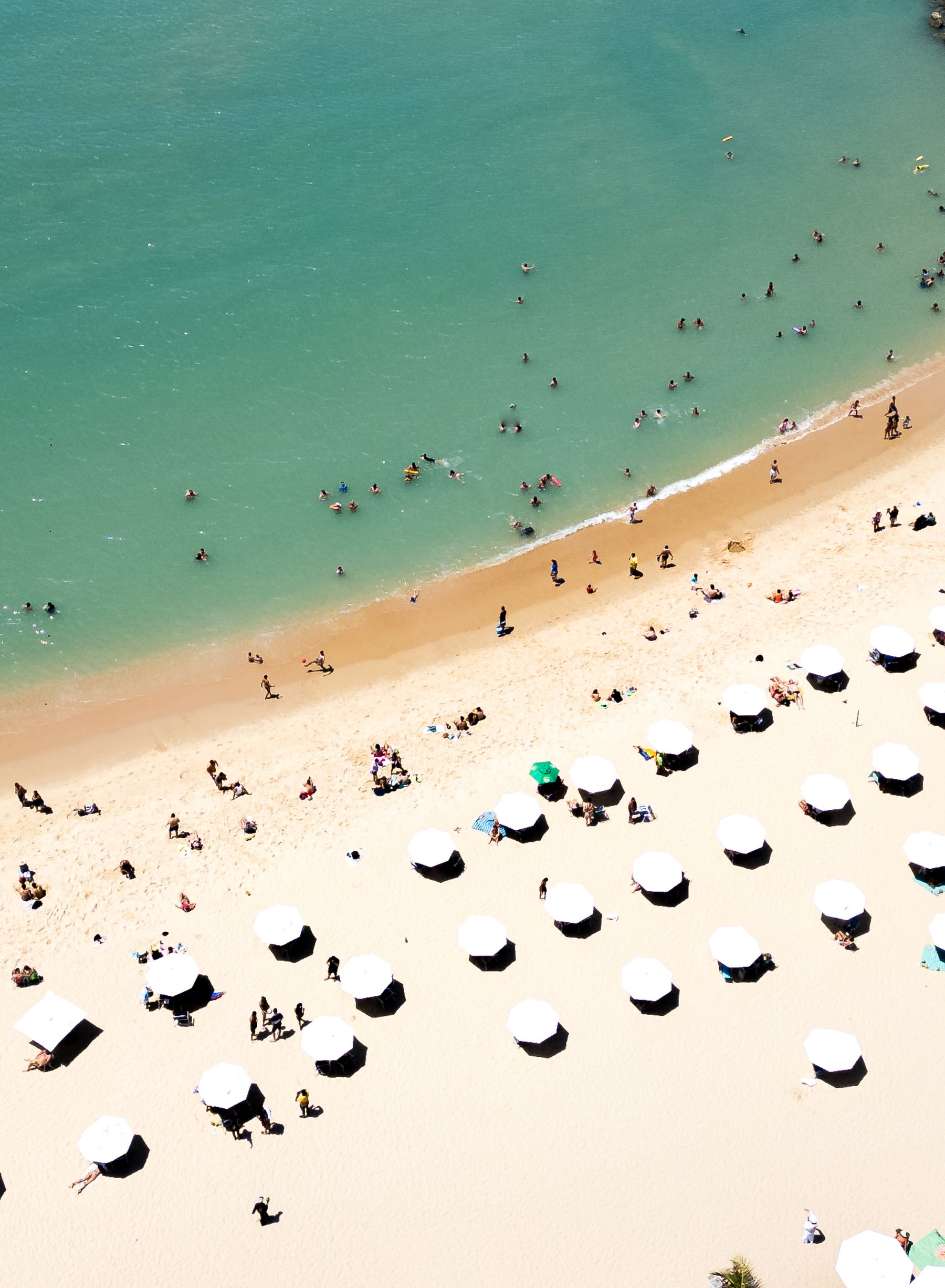Aerial view of a lively beach with people enjoying the sun and sea