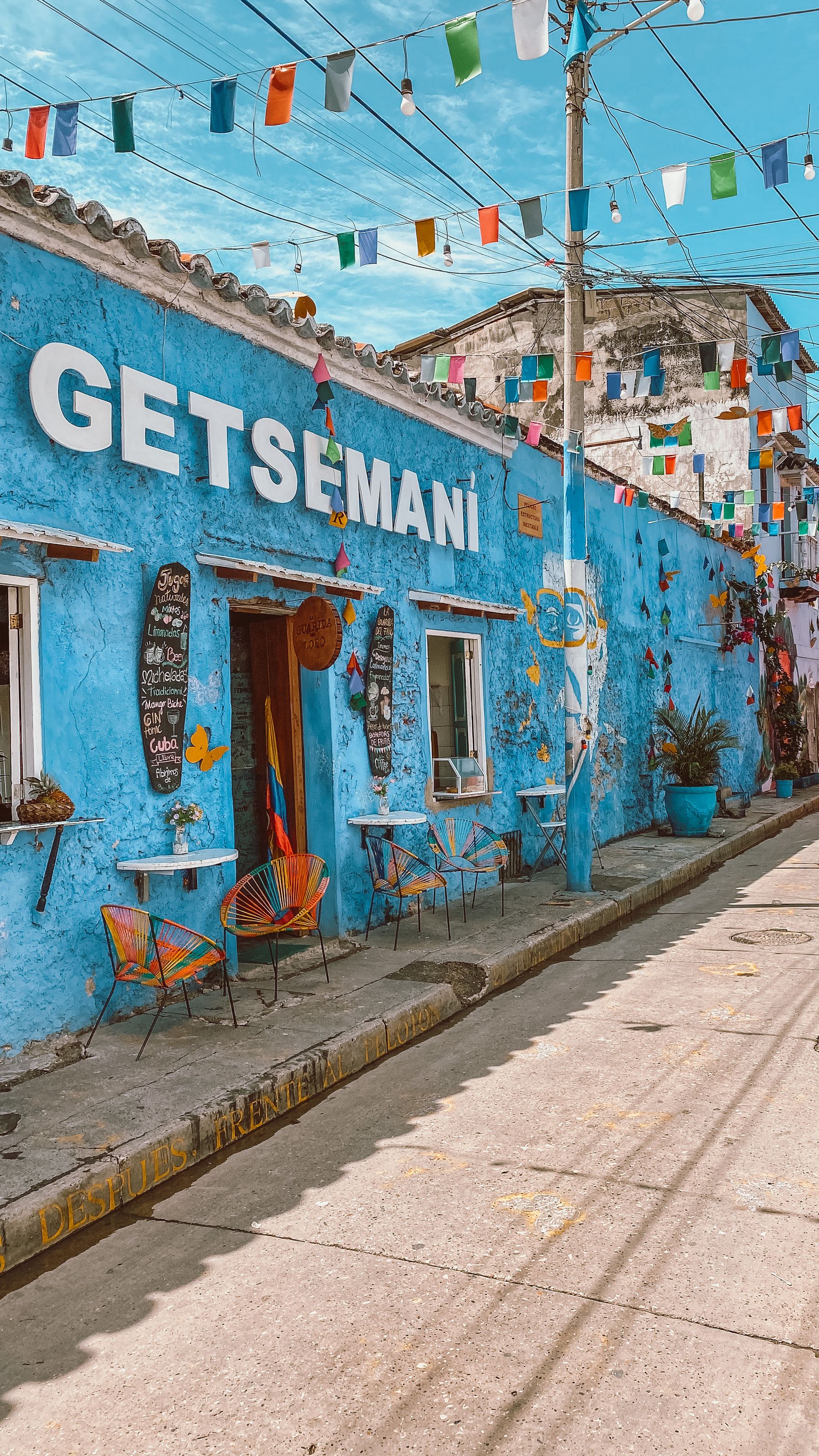 A bright blue facade in Getsemani, Cartagena hung with flags and decorations