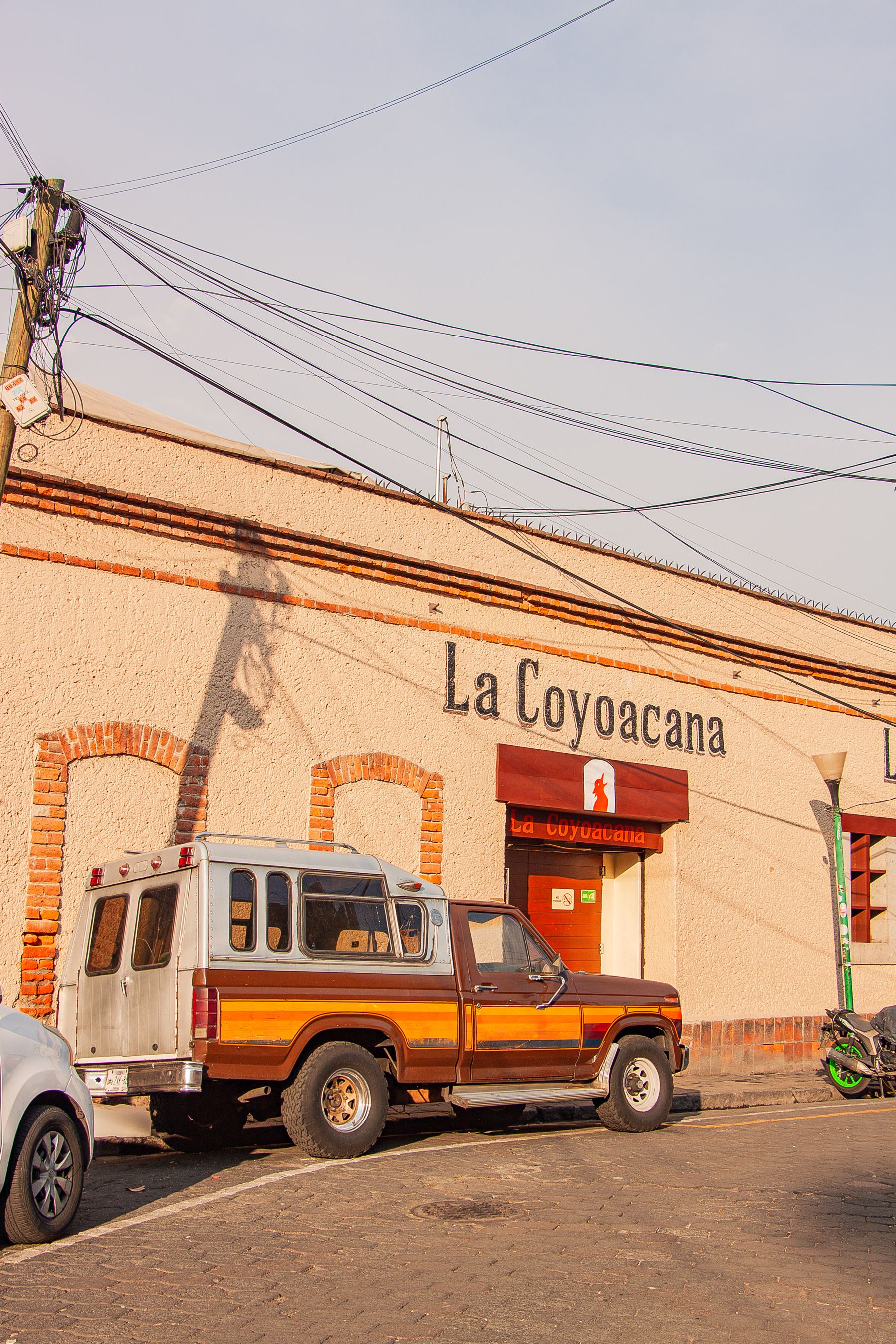 A classic Mexico City cantina with a vintage car parked outside in warm sunlight