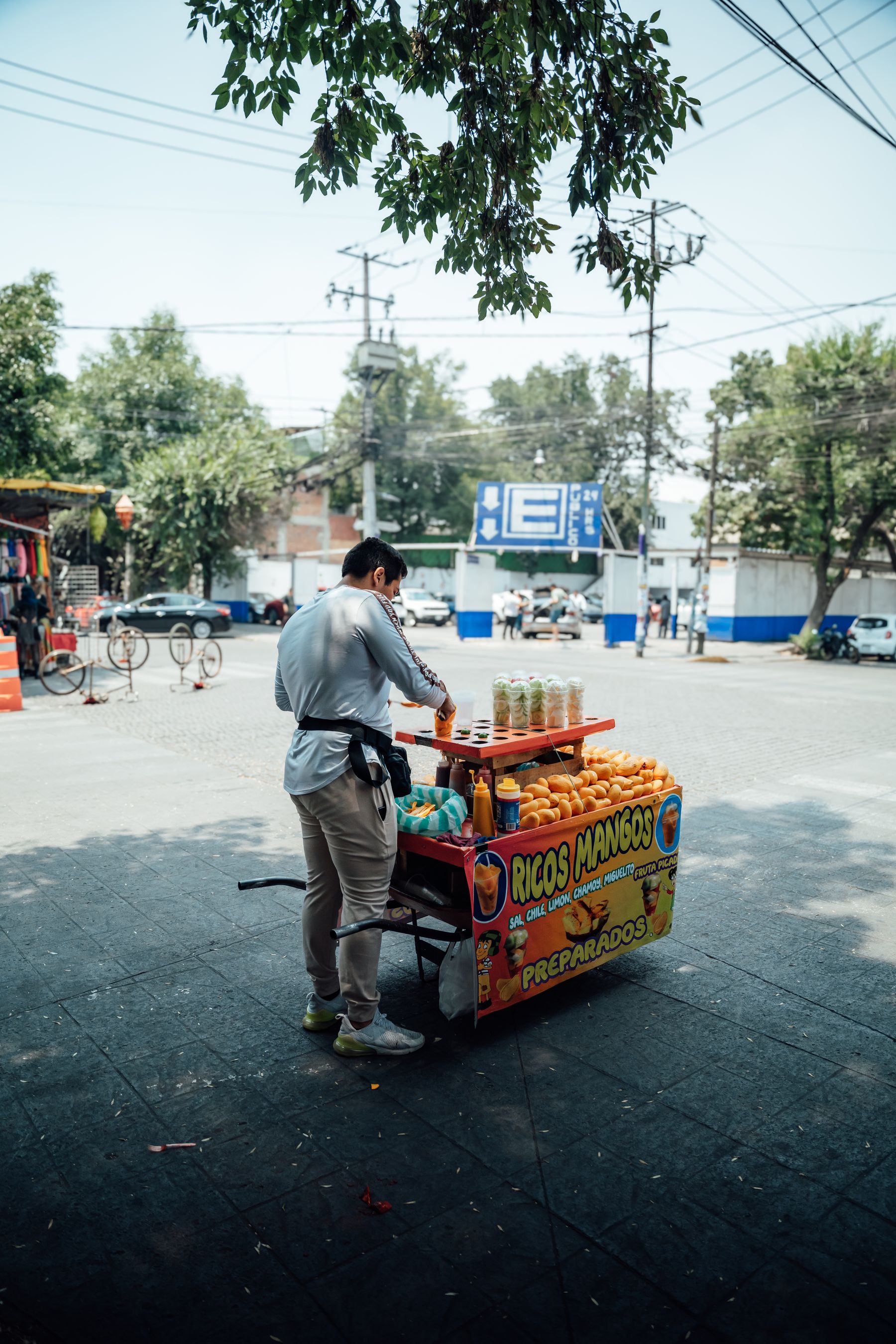 A street vendor selling mangoes on a sunny Mexico City street
