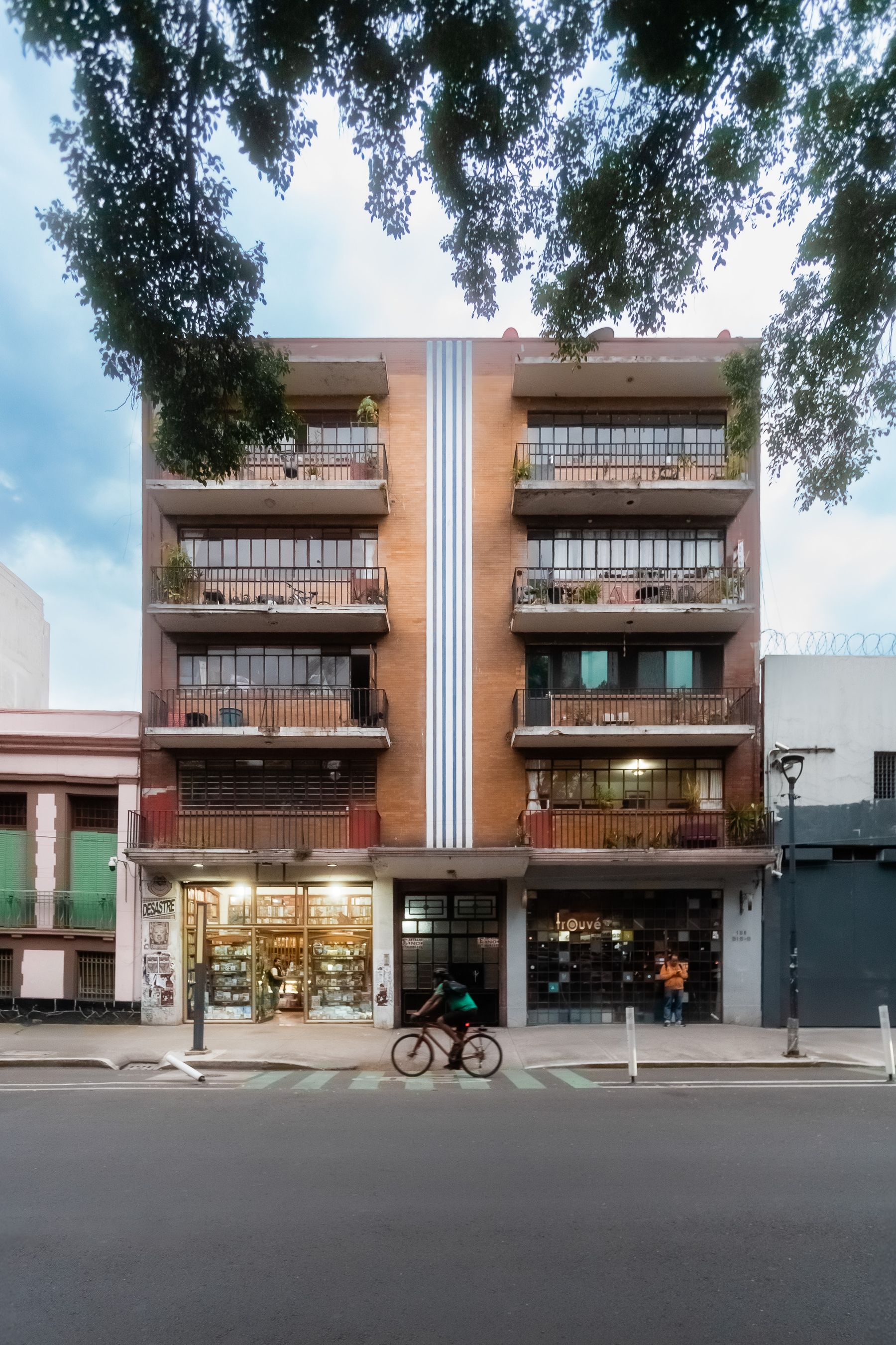 A modern residential building on a Mexico City street with a cyclist passing