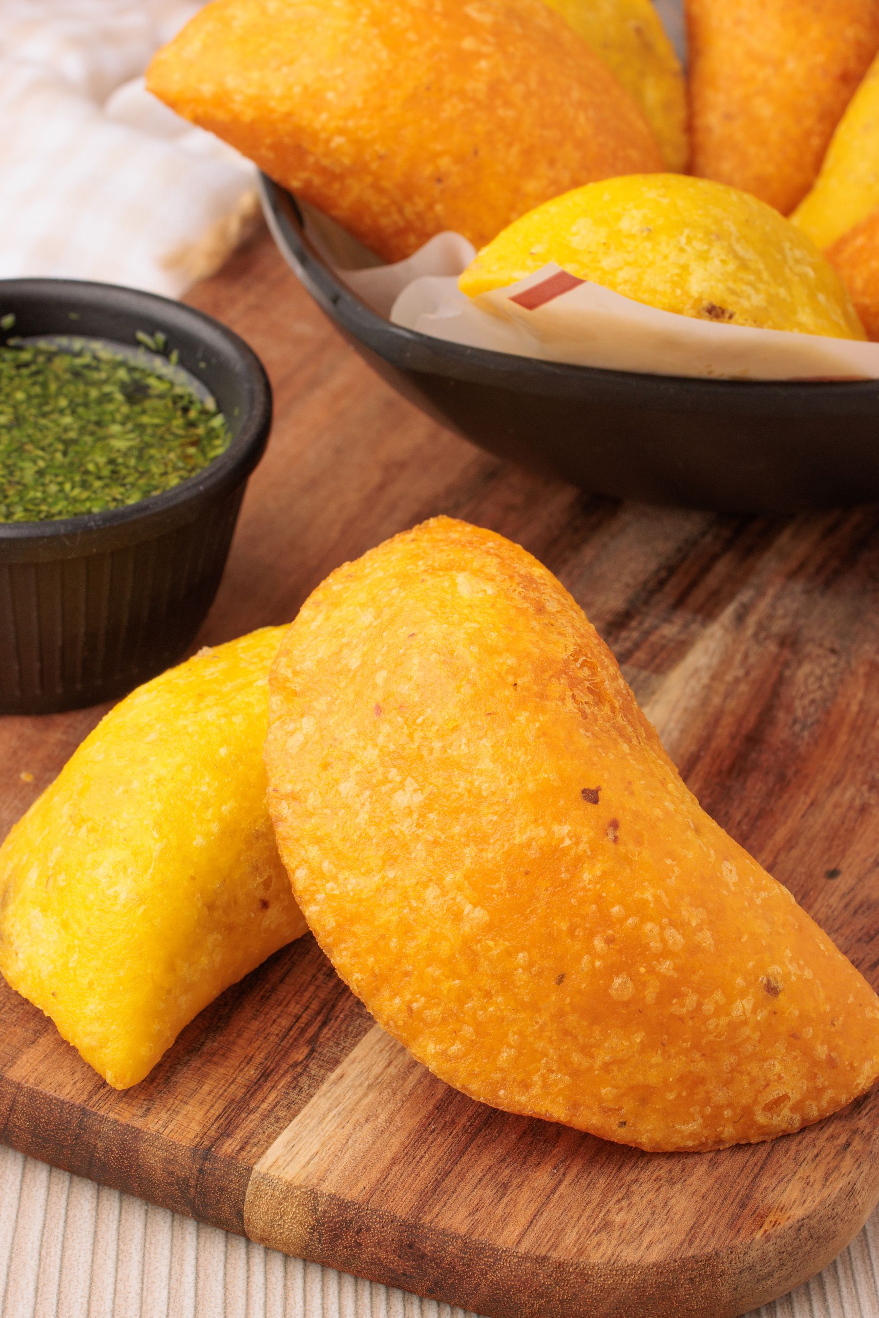 Colombian empanadas with dipping sauce on a wooden board