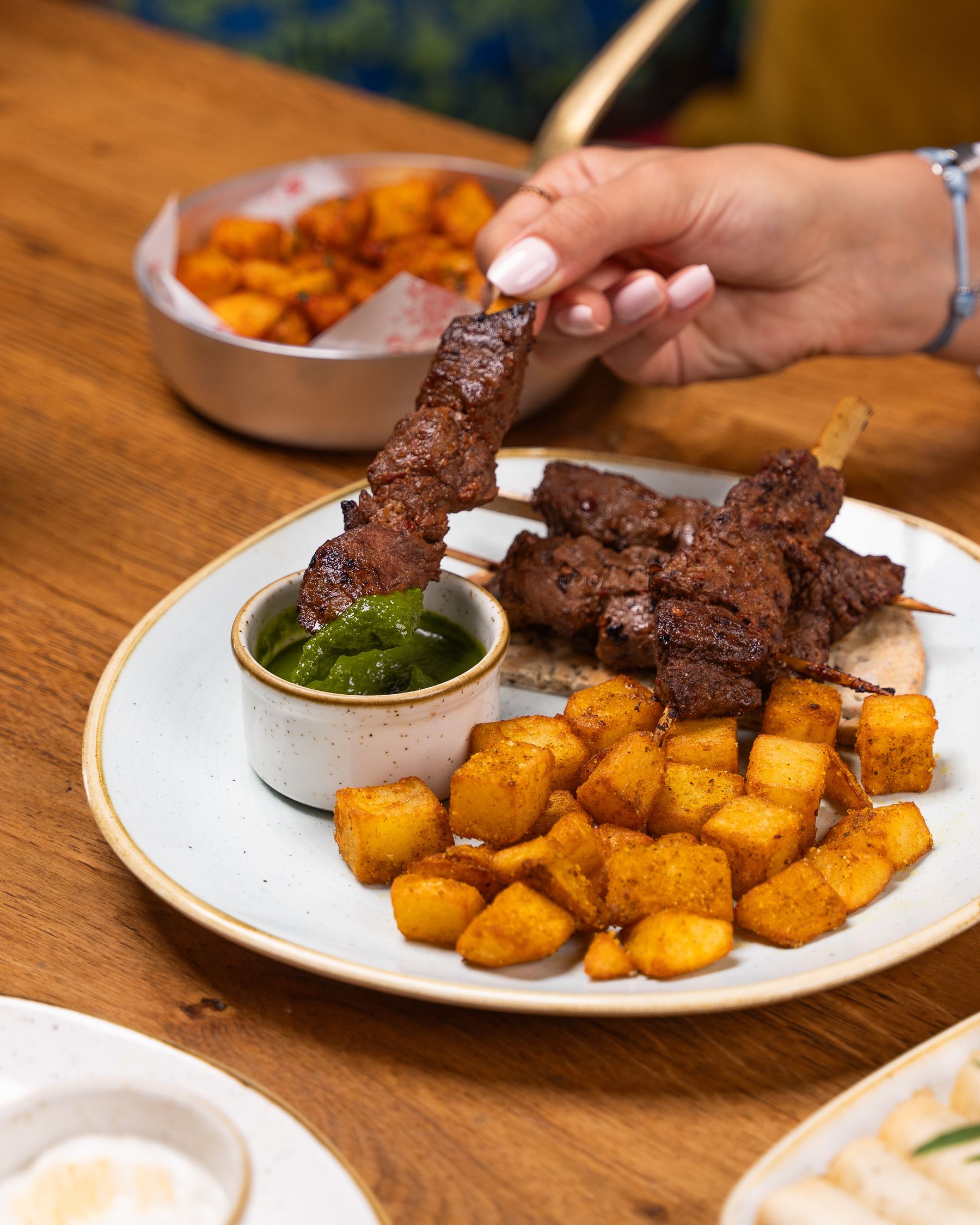 Grilled meat skewers with seasoned potatoes and a dipping sauce