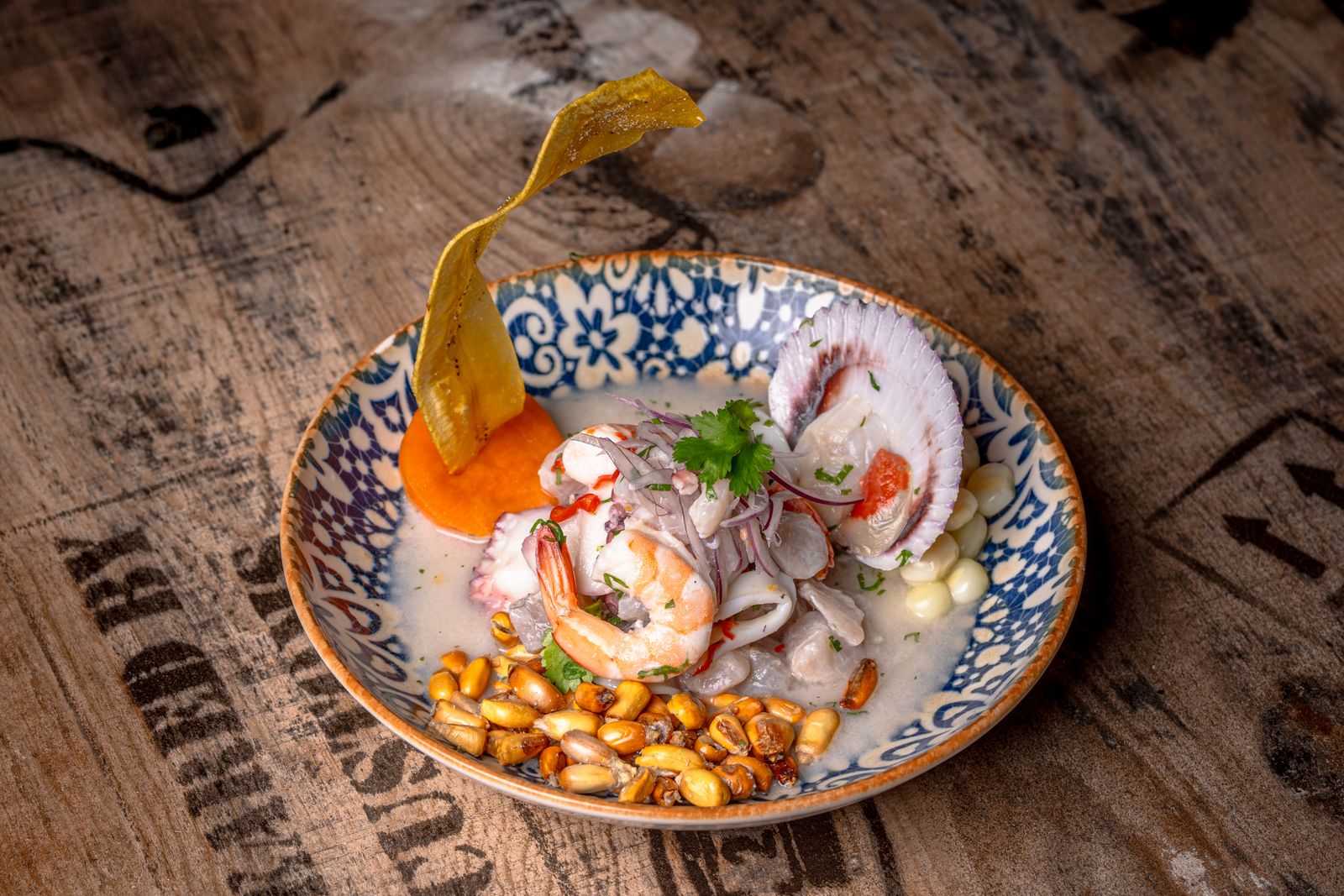 Peruvian ceviche with shrimp, leche de tigre and corn on a patterned plate