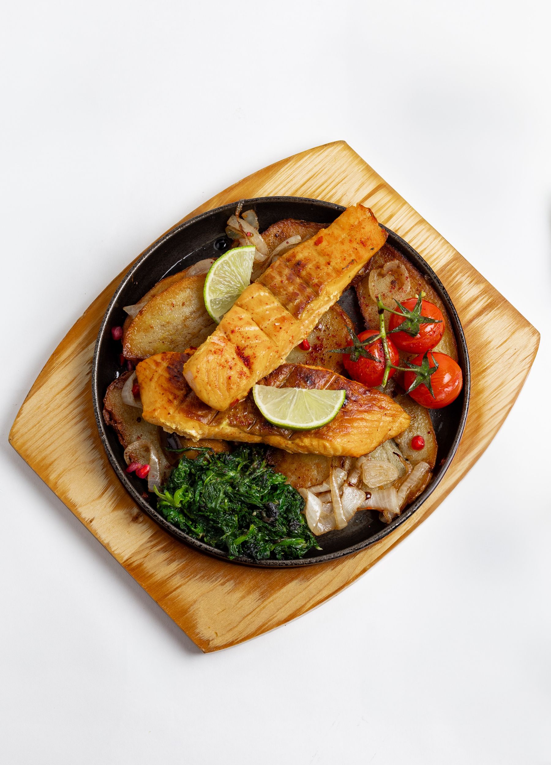 Grilled fish served with roasted vegetables and lime on a wooden board