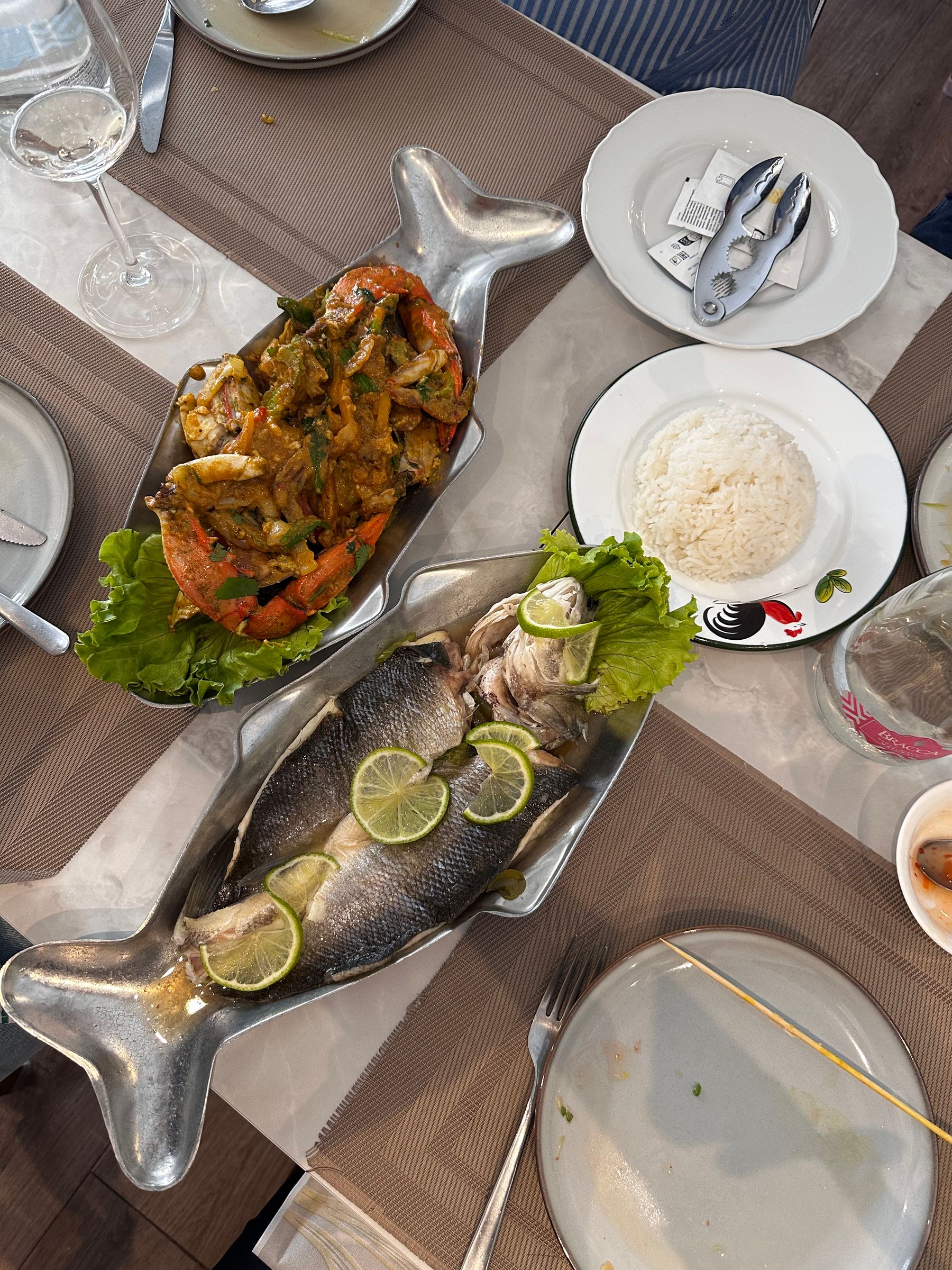 A top-down seafood spread of grilled fish, vegetables, rice and drinks
