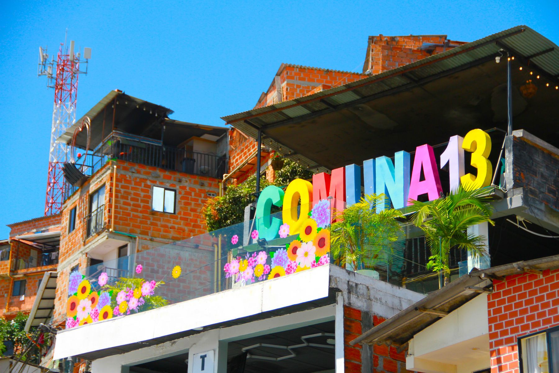 Brightly painted murals along a street in Comuna 13, Medellin, with visitors walking past