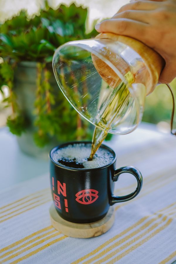 Pour-over coffee being brewed into a black mug