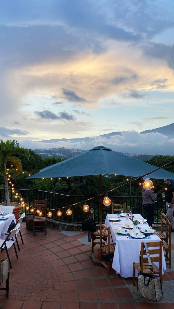 Hillside restaurant terrace with string lights and a sunset valley view