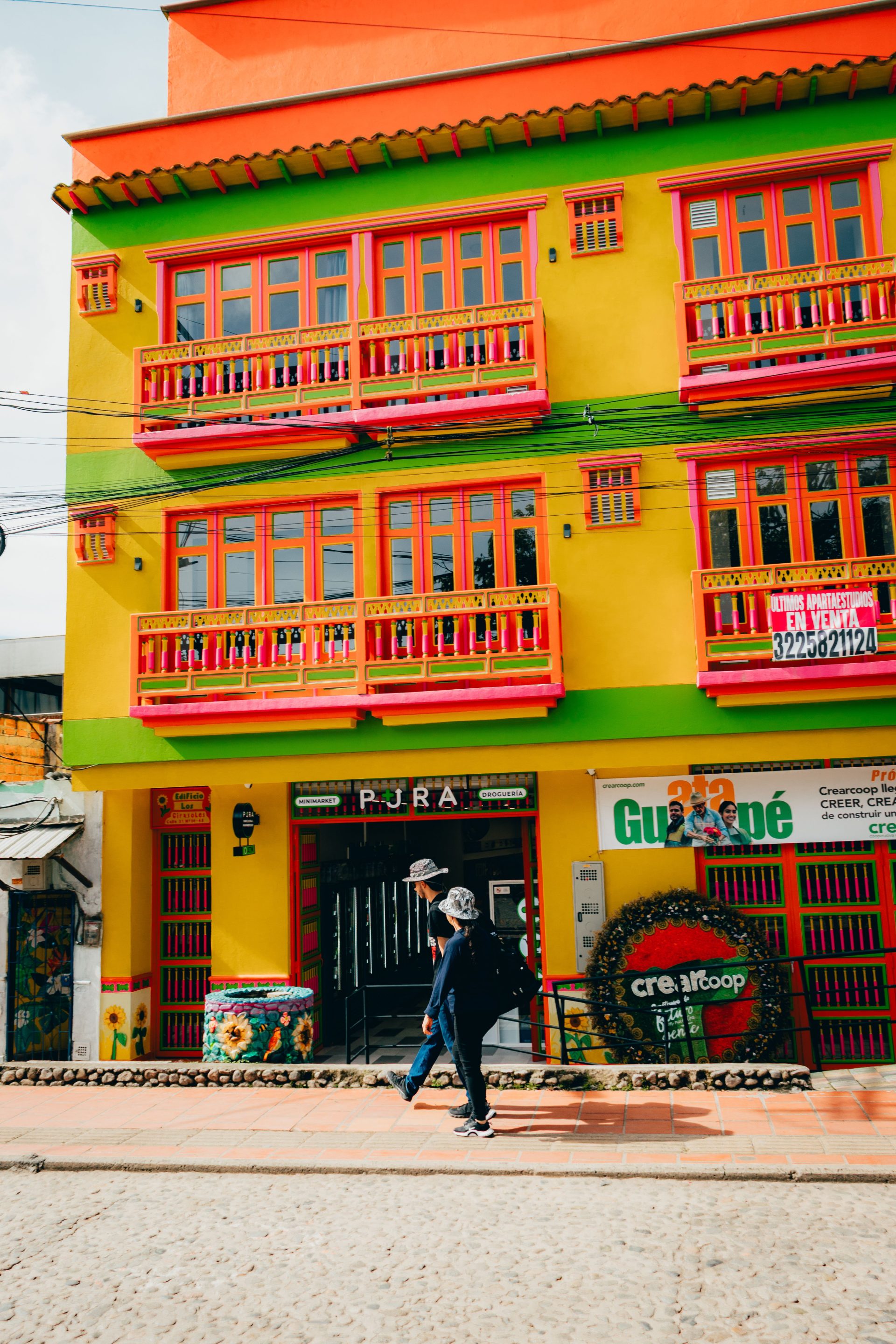 A brightly painted building with zócalo panels on a street in Guatapé