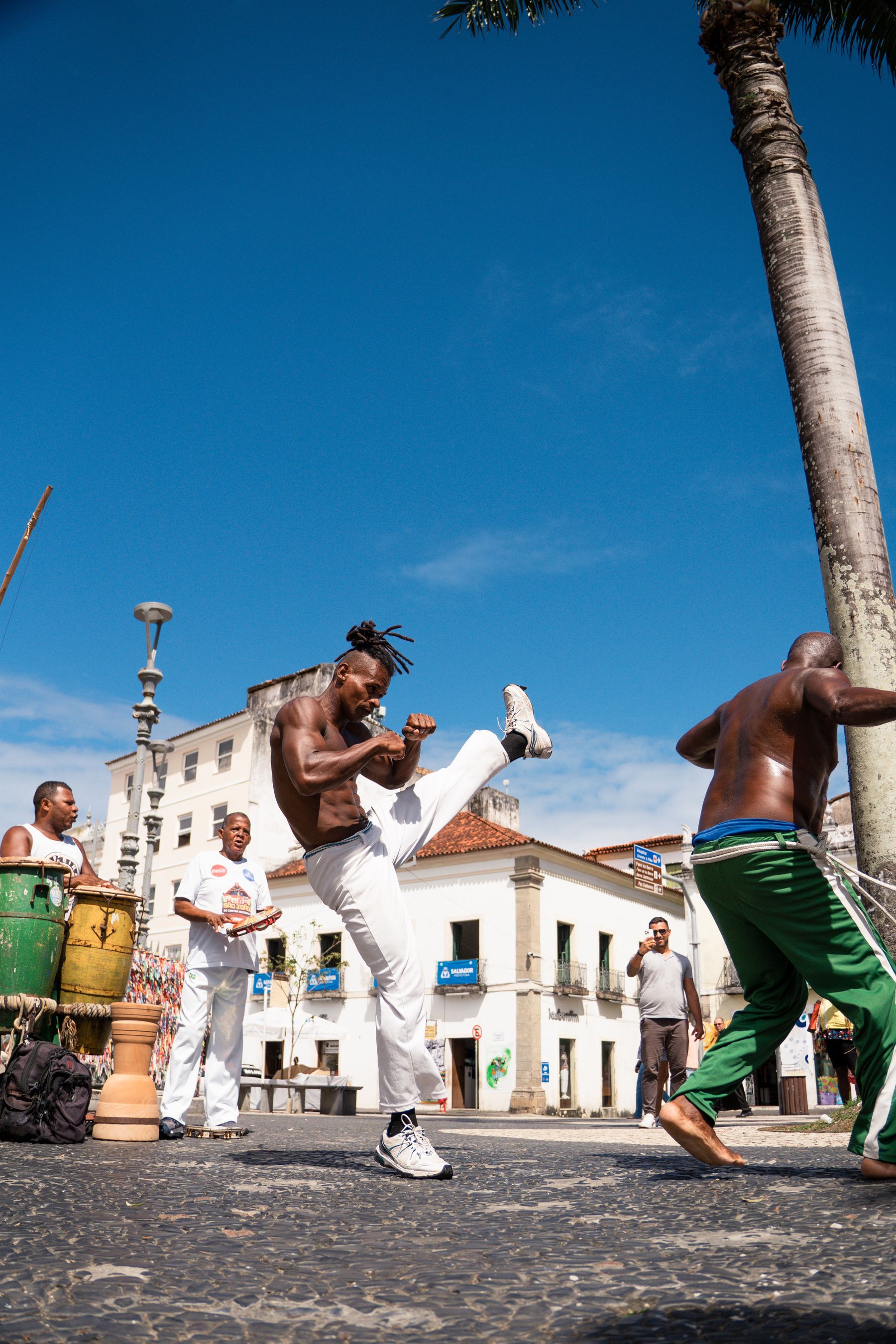 Musicians playing drums outdoors in the afternoon as a circle forms
