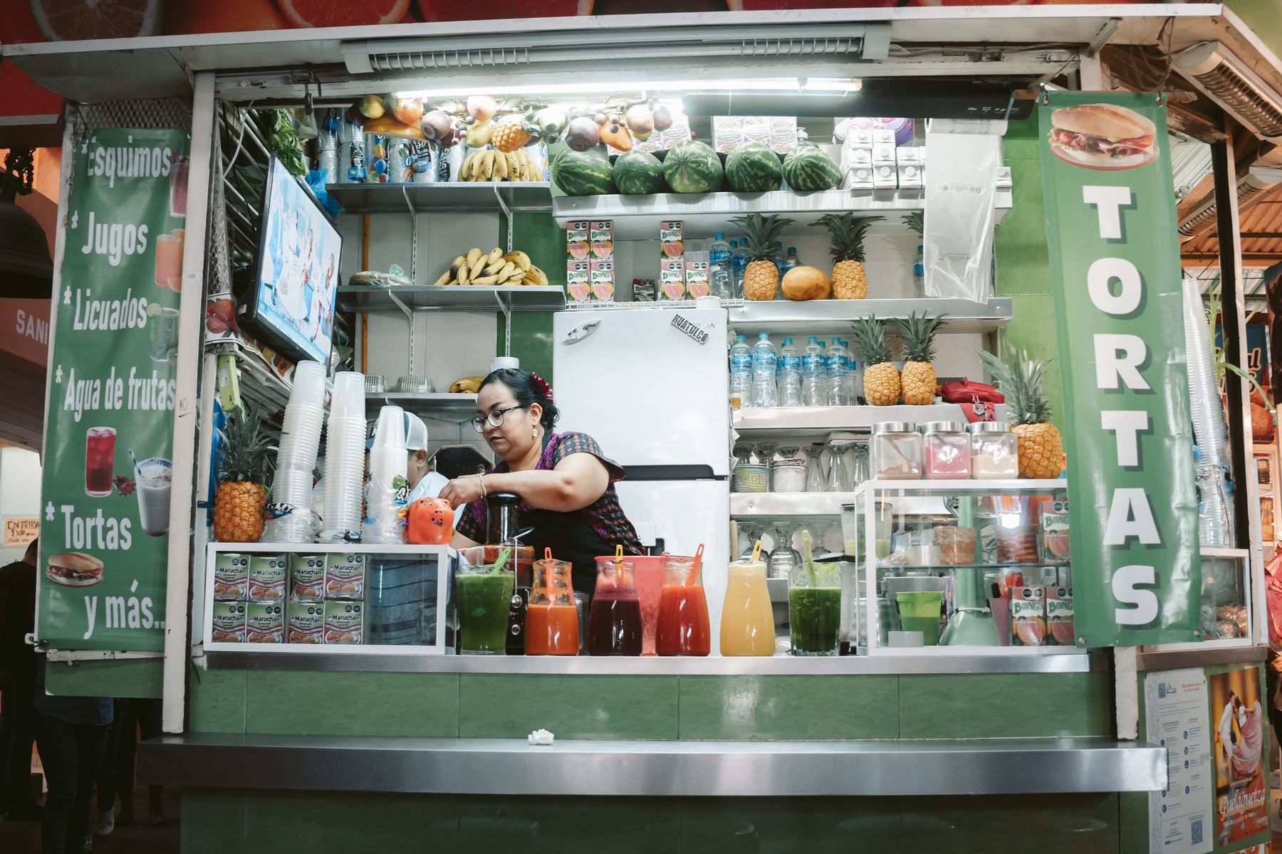 A colourful juice stand with fresh fruit and drinks in an Oaxaca market