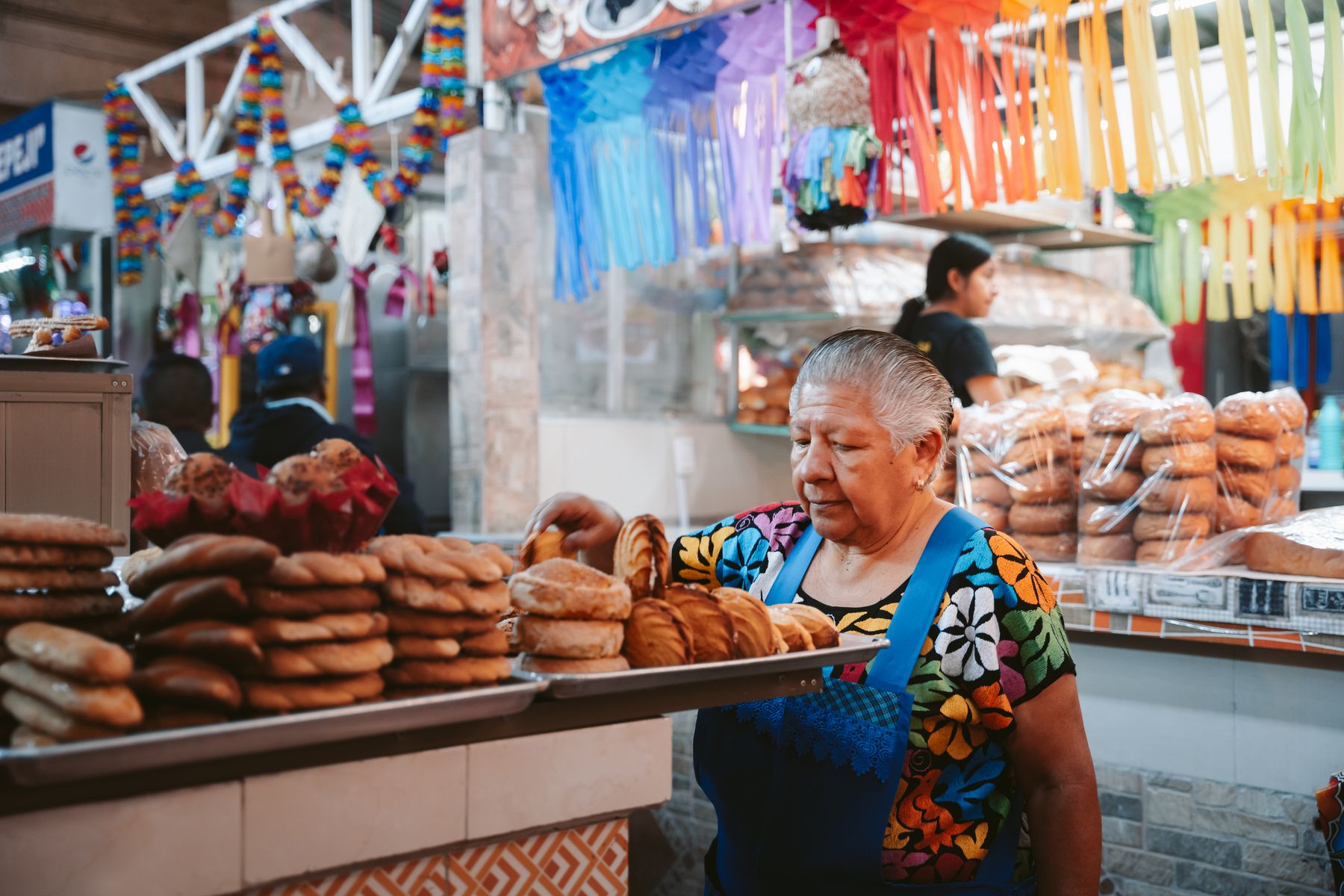 An elderly woman working at a bakery stall in a market in Oaxaca, Mexico