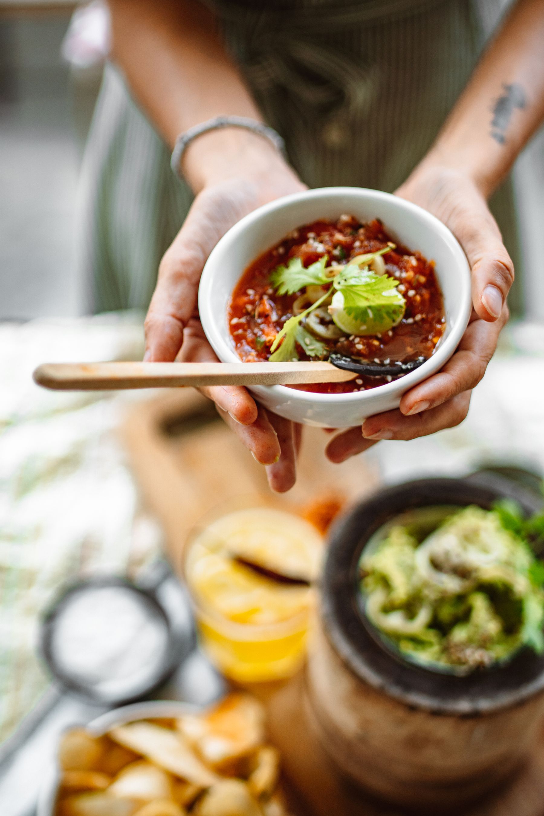 A person holding a bowl of spicy salsa garnished with coriander