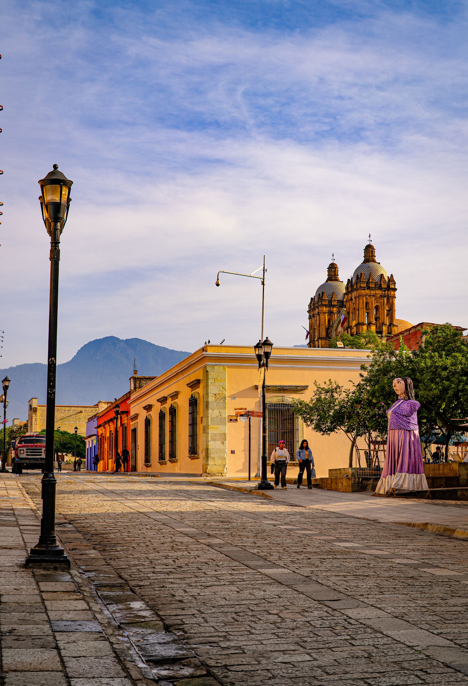 A picturesque street in Oaxaca with vibrant buildings and a church at the end