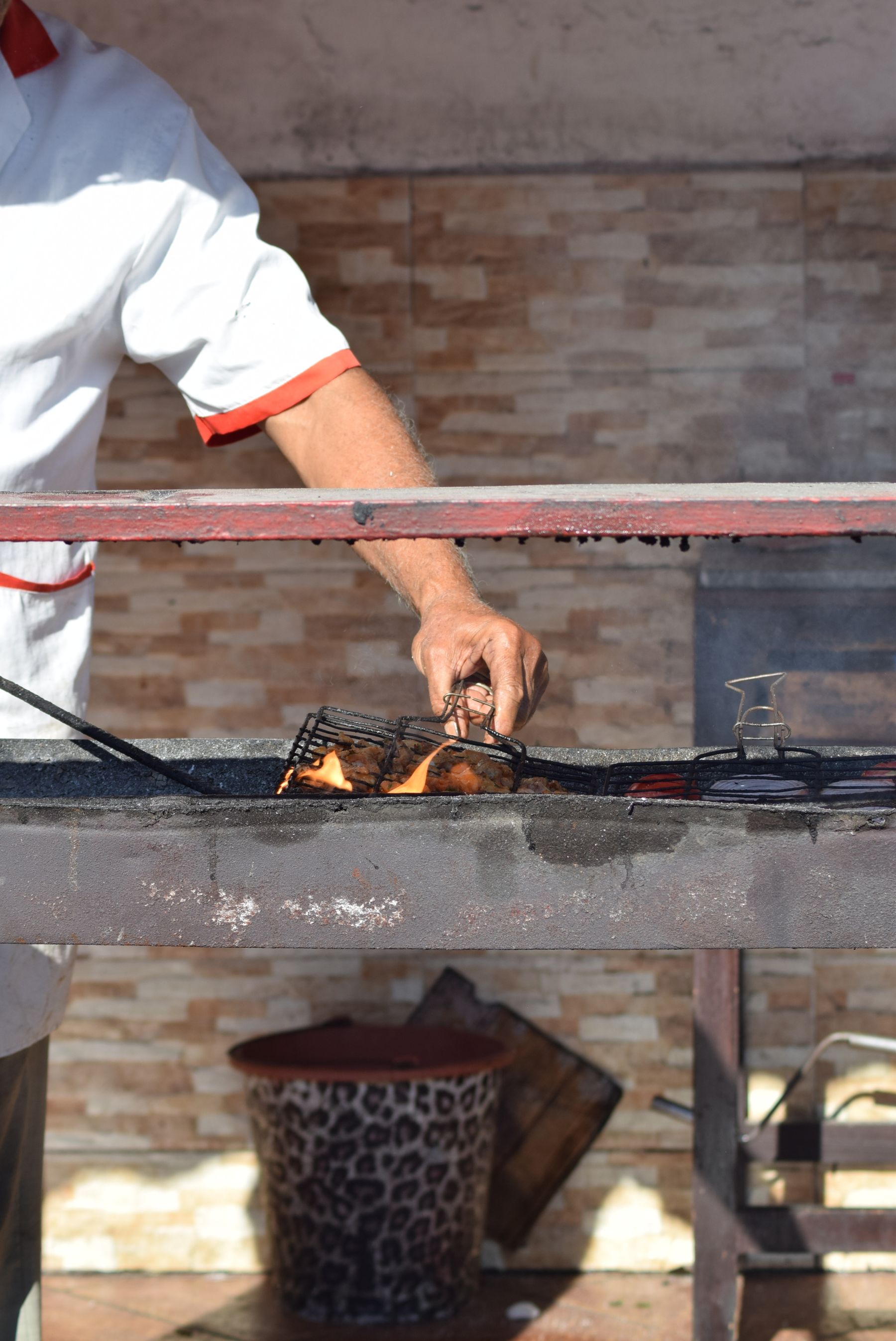 A street vendor grilling food outdoors on a traditional barbecue