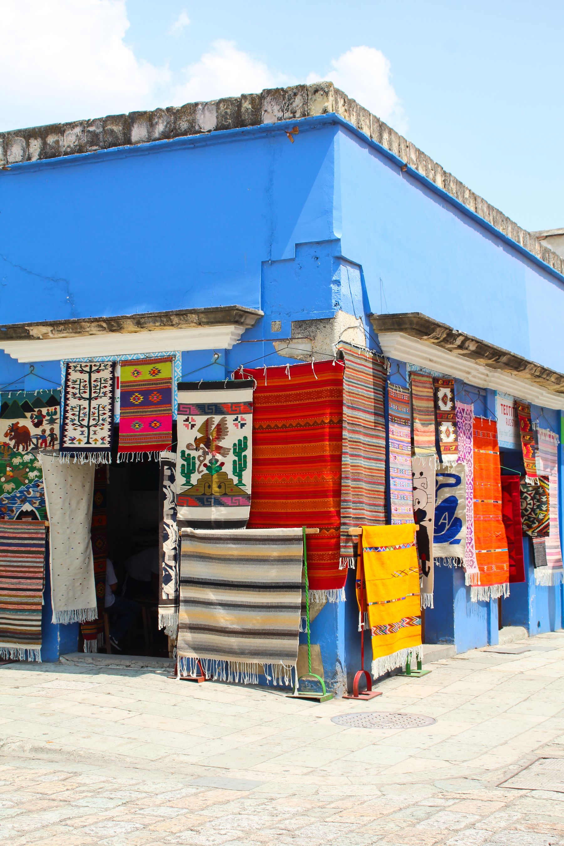 Traditional Mexican textiles hanging on a blue building facade in Oaxaca