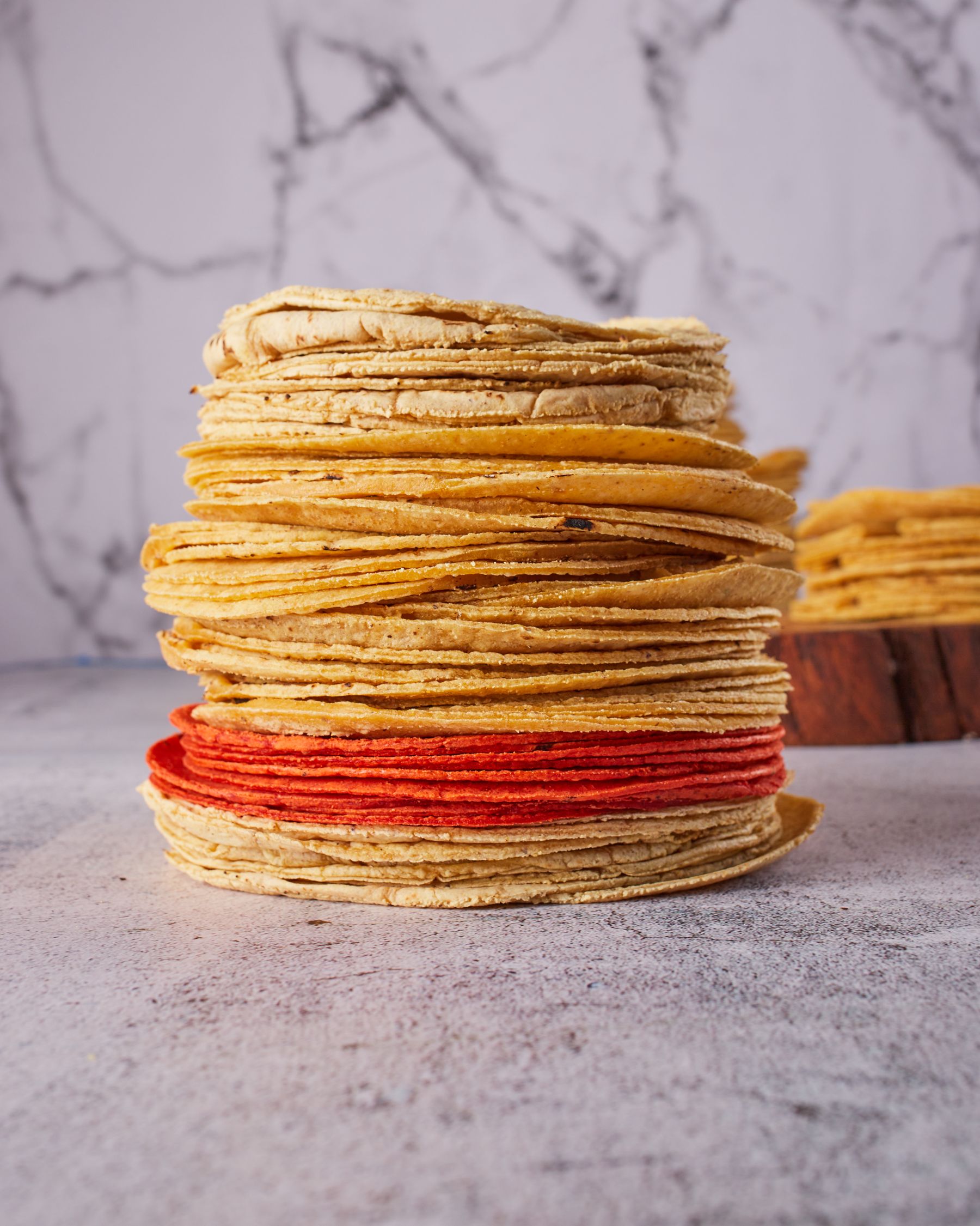 A tall stack of fresh corn tortillas on a kitchen counter