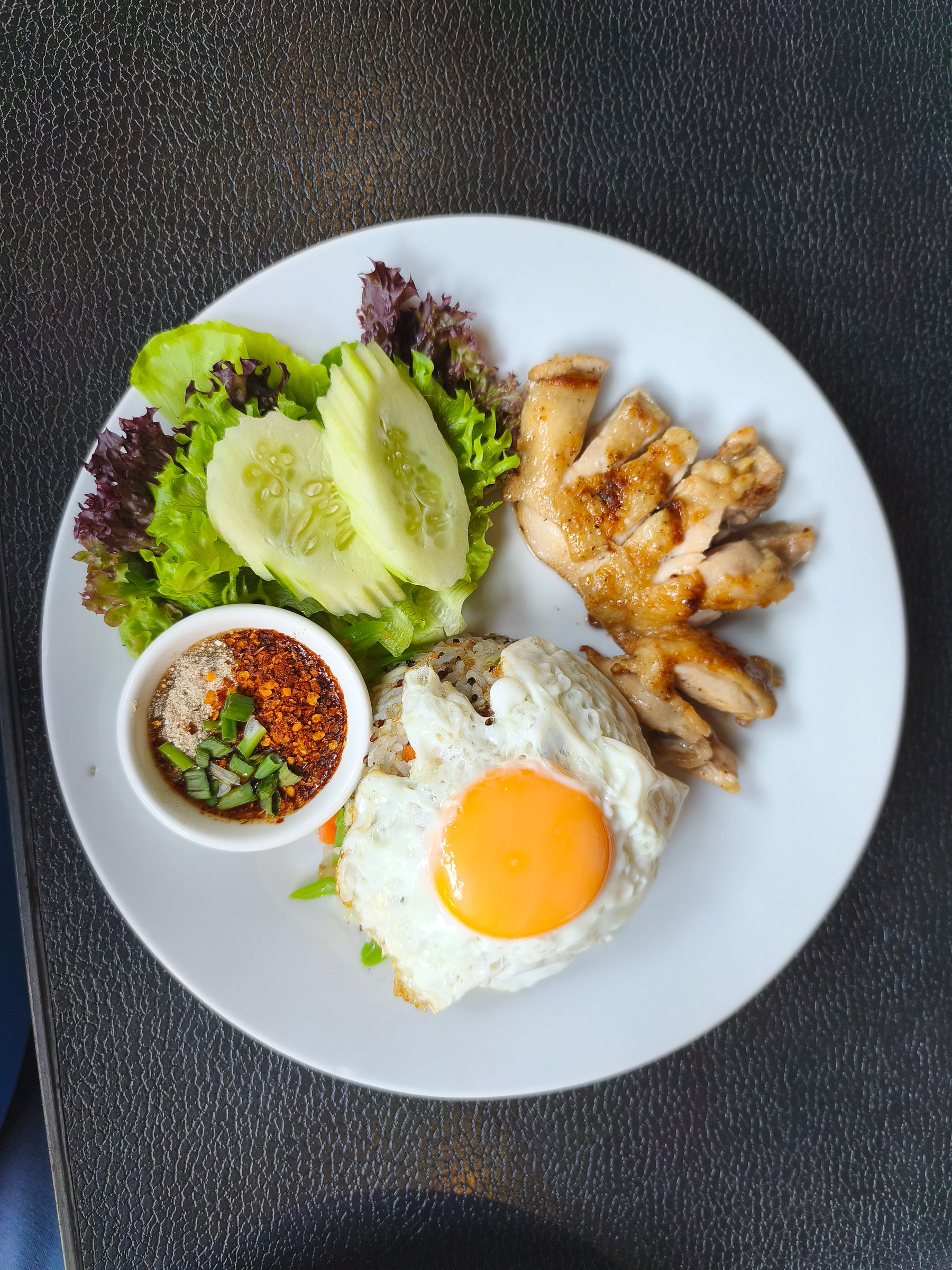 A Thai chicken rice set with fresh vegetables and a fried egg