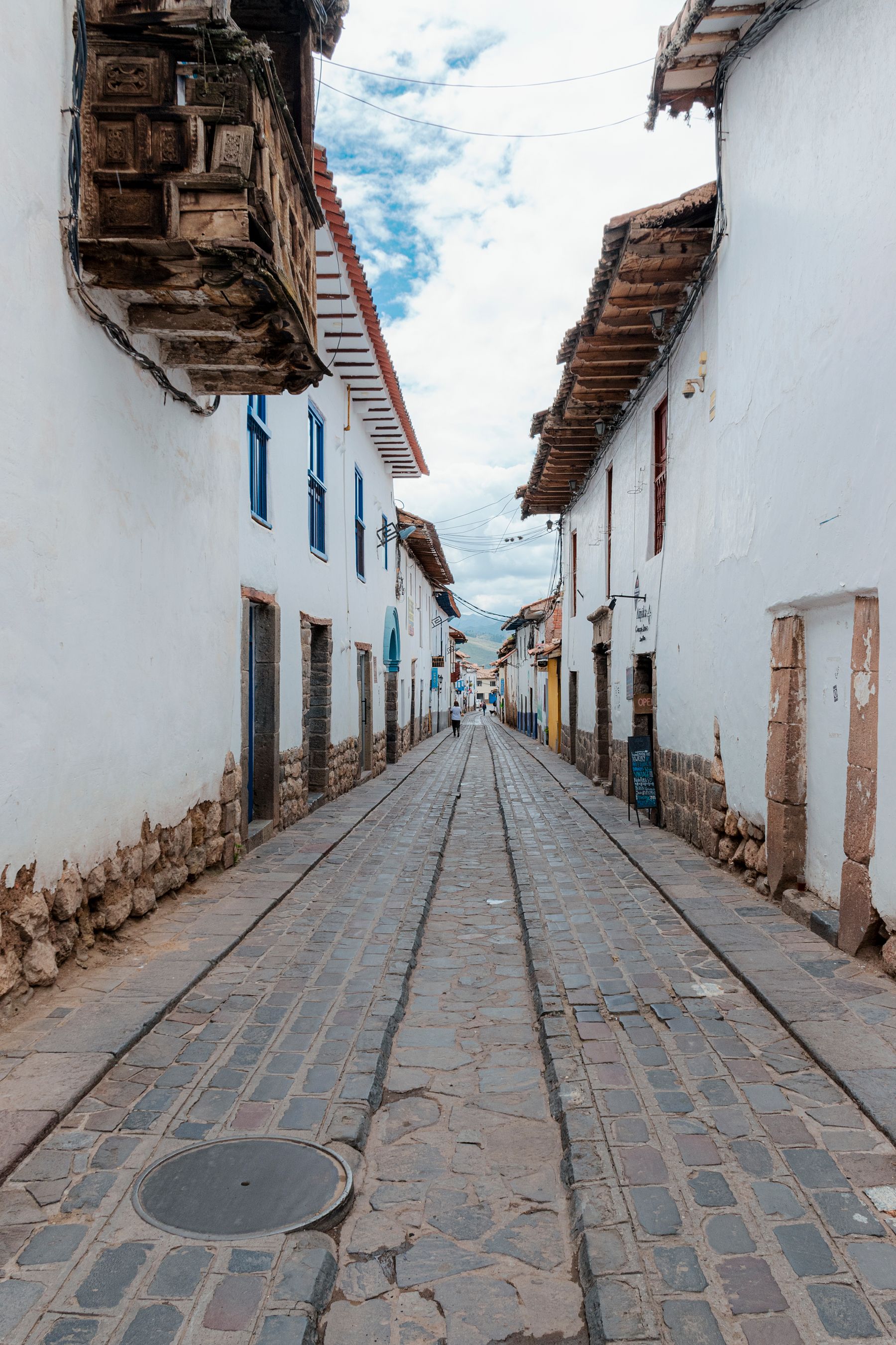 A narrow cobblestone street in Cusco, Peru lined with traditional stone buildings