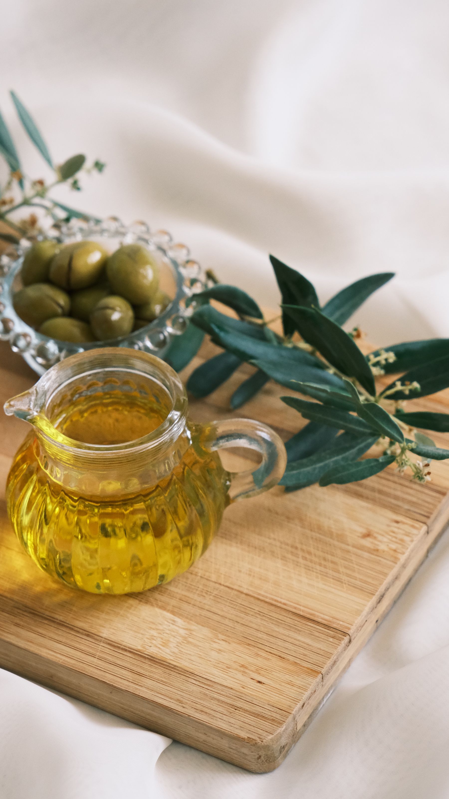 A jar and bottle of olive oil on a wooden board