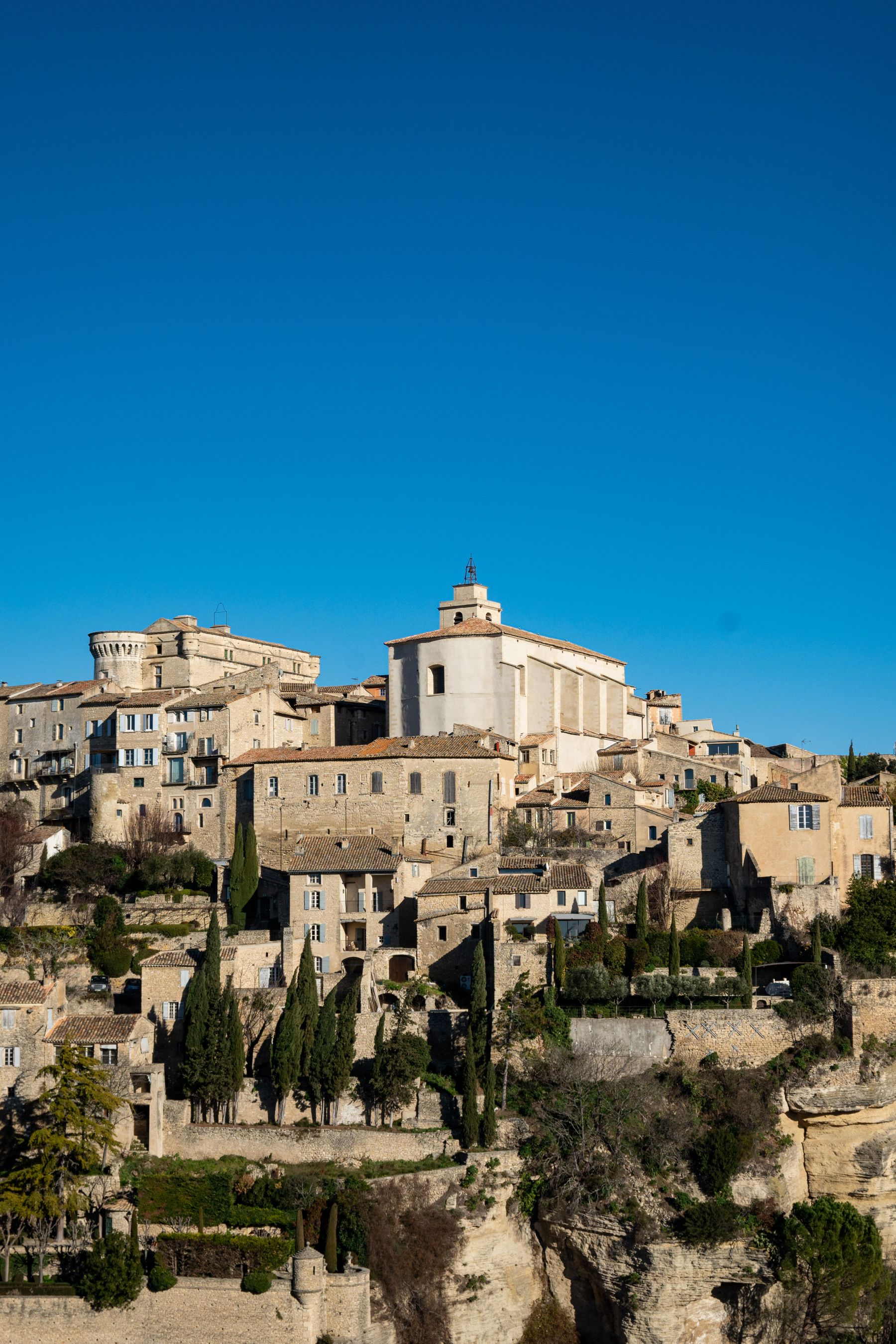 A perched stone village on a hillside under a clear blue sky