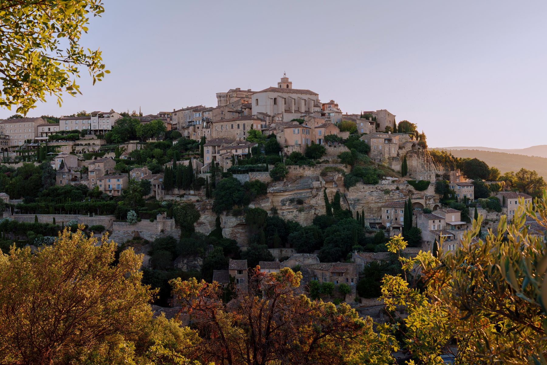 A stone village built into a rock face above a wooded valley