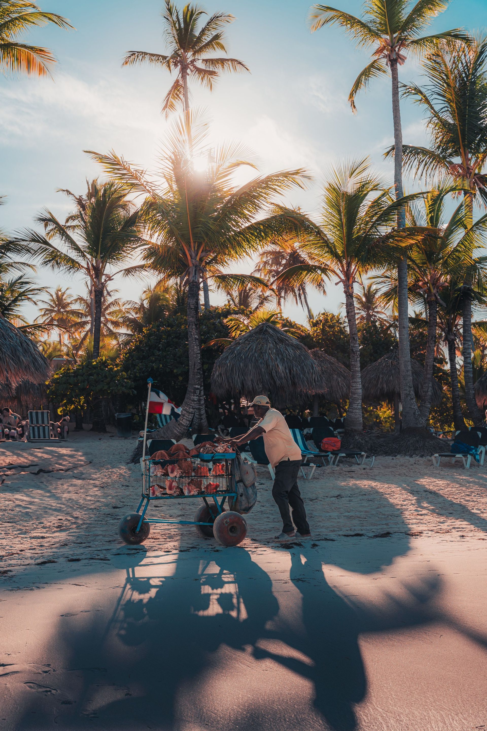 A vendor pushing a cart along a sunlit beach in Punta Cana