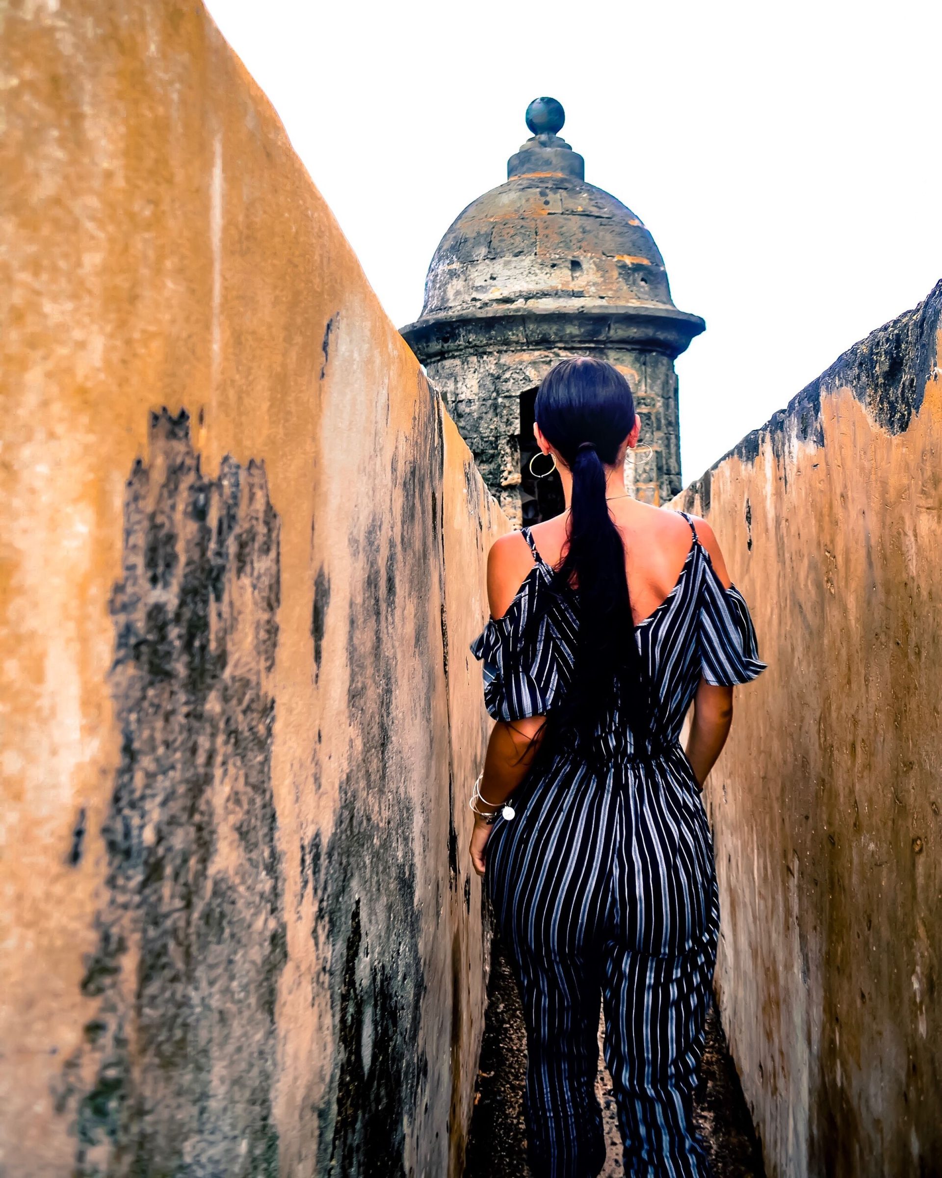 A woman walking along the historic sandstone walls of San Juan, Puerto Rico