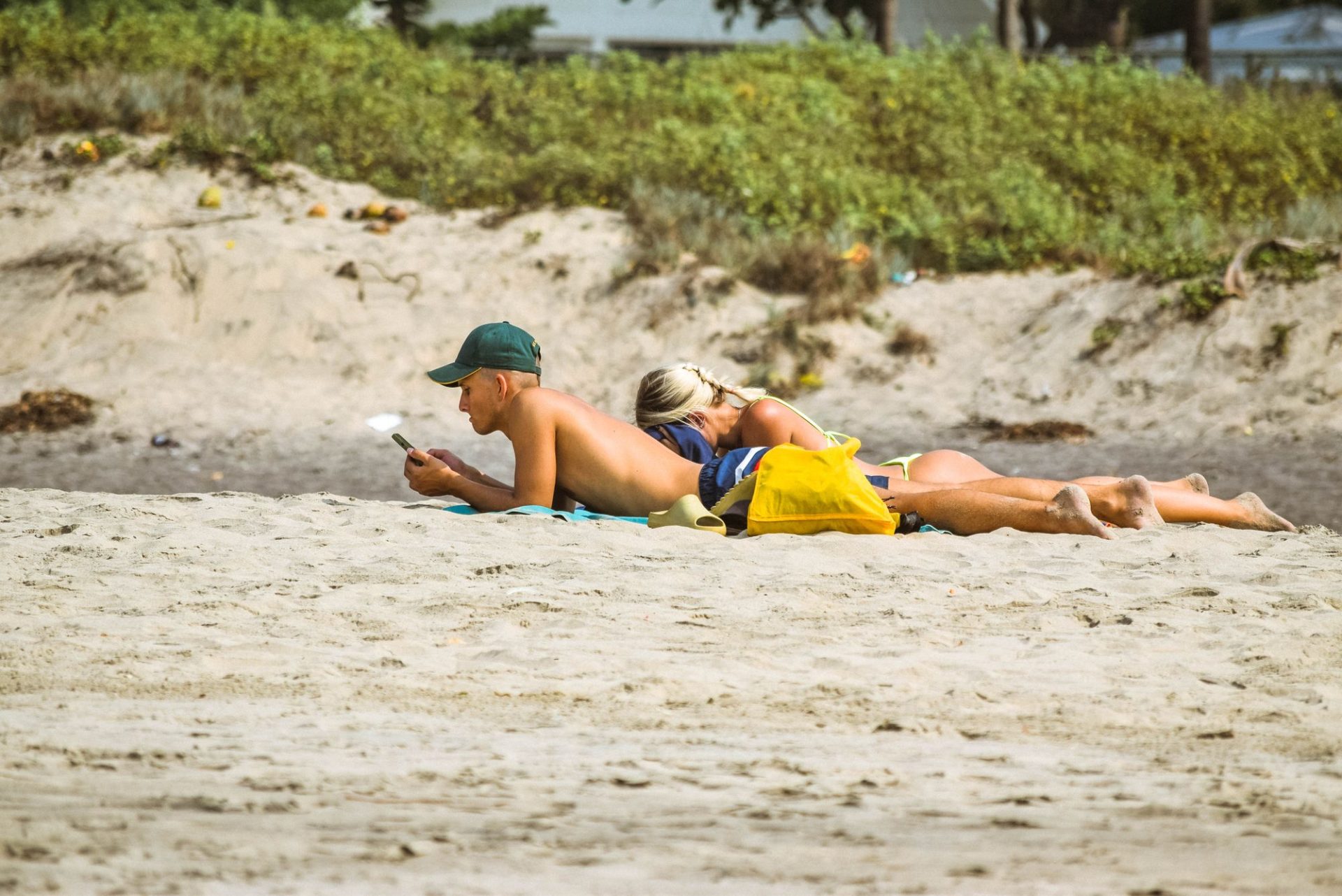 Passengers waiting on the sand beside a wooden boat