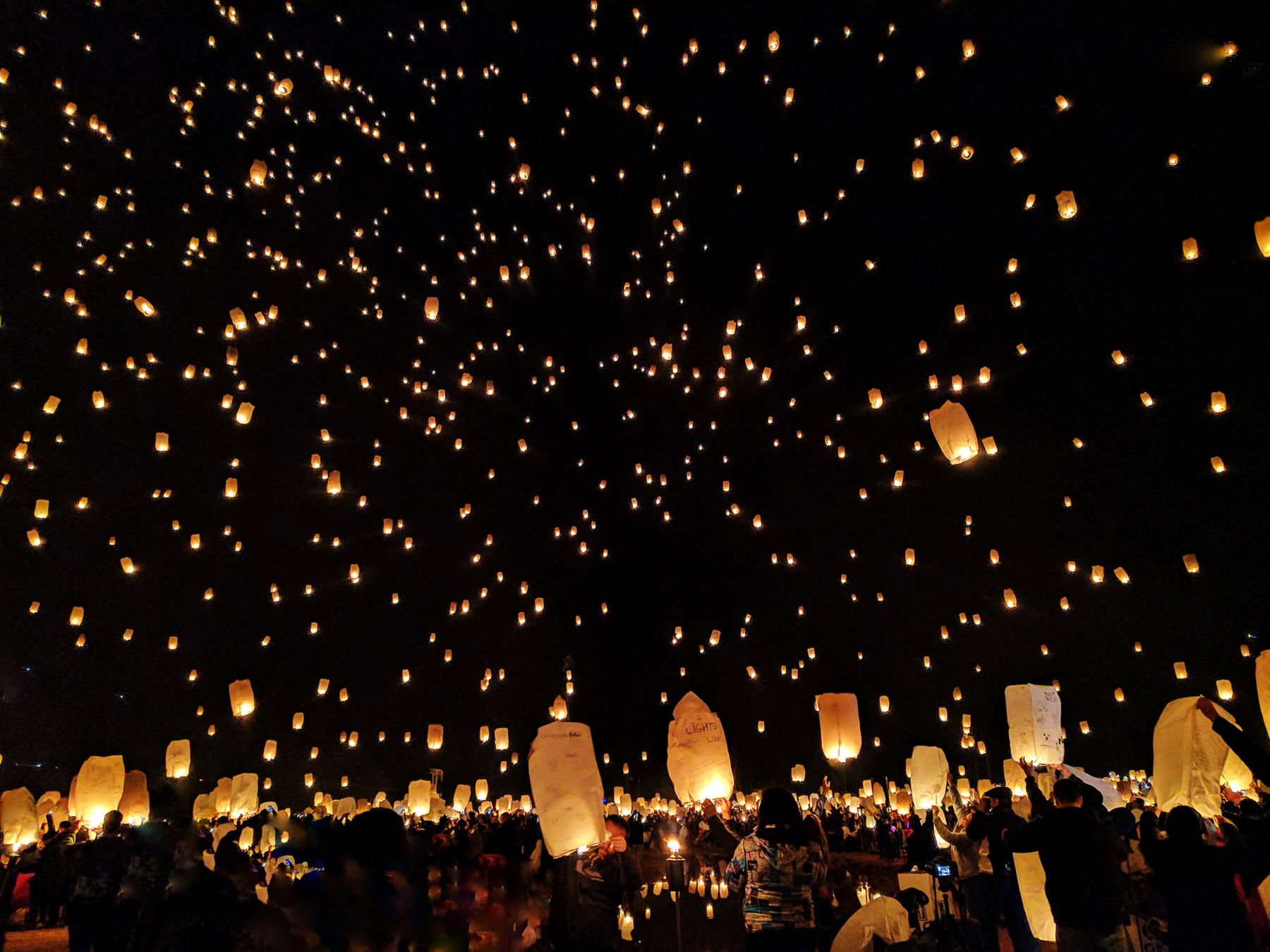 Paper lanterns rising into a night sky