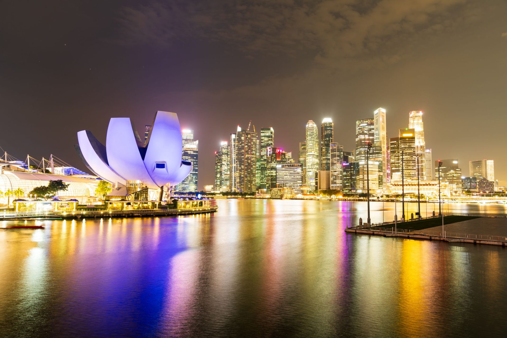 Singapore&rsquo;s Marina Bay skyline lit at night, reflected across the water